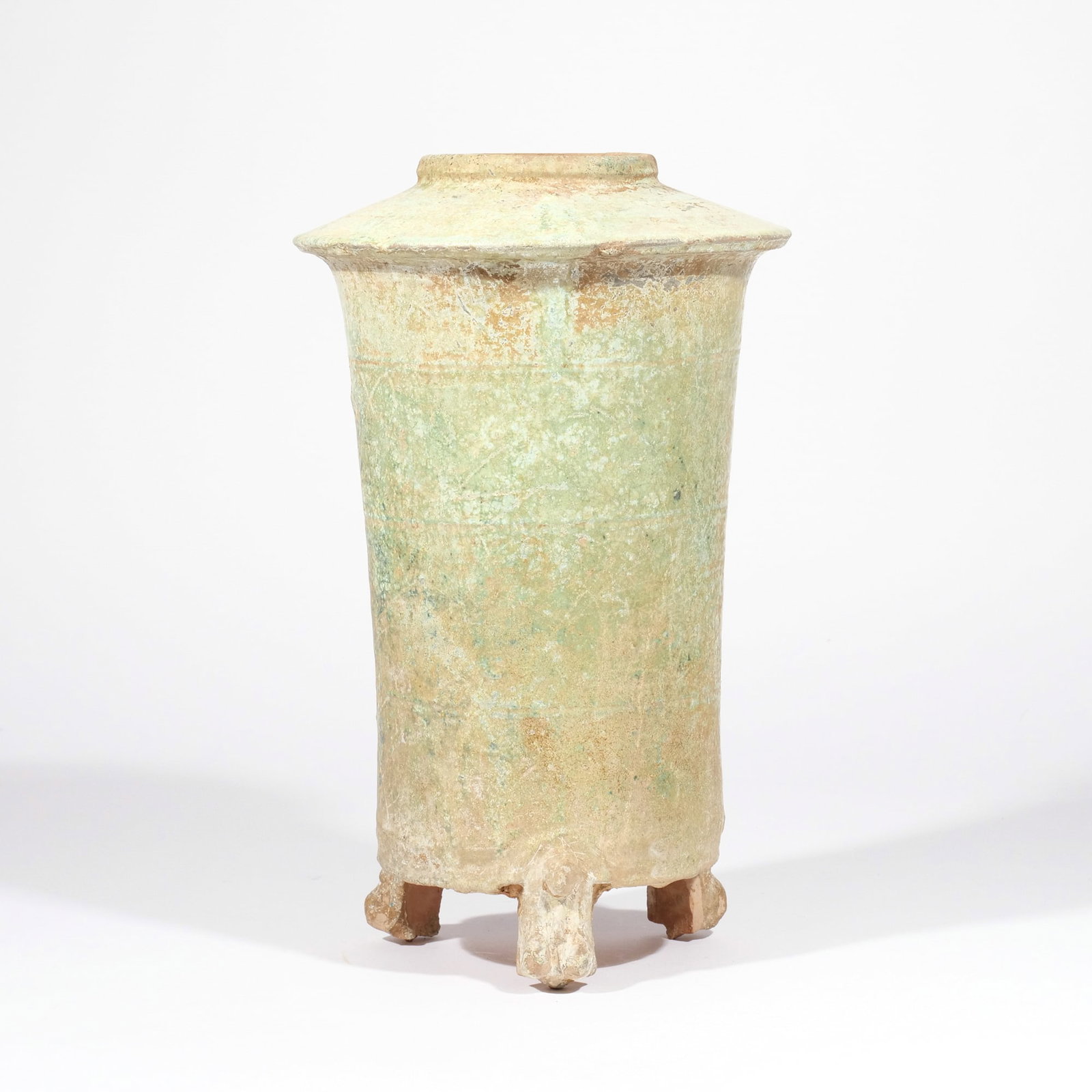 CHINESE HAN DYNASTY GRANARY JAR: Han dynasty (202 BC - 220 AD), of flaring cylindrical shape with overhanging top and three shaped feet, covered in a light green glaze h. 12-1/2 in. Provenance: Property of a lifelong collector of Chi