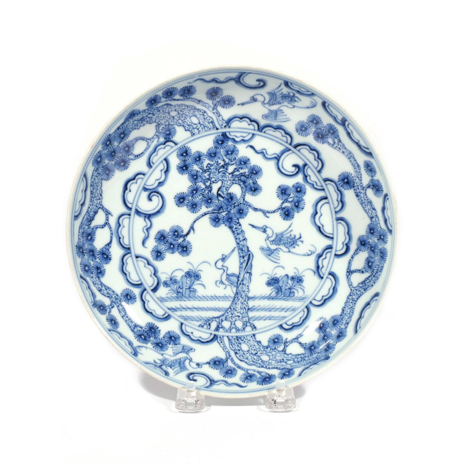 CHINESE BLUE & WHITE PORCELAIN DISH: Qing dynasty (1644-1911), depicting a pine with two cranes, one poised in flight, the other standing, in a springtime landscape, and an additional two cranes with pine in flight among clouds around th
