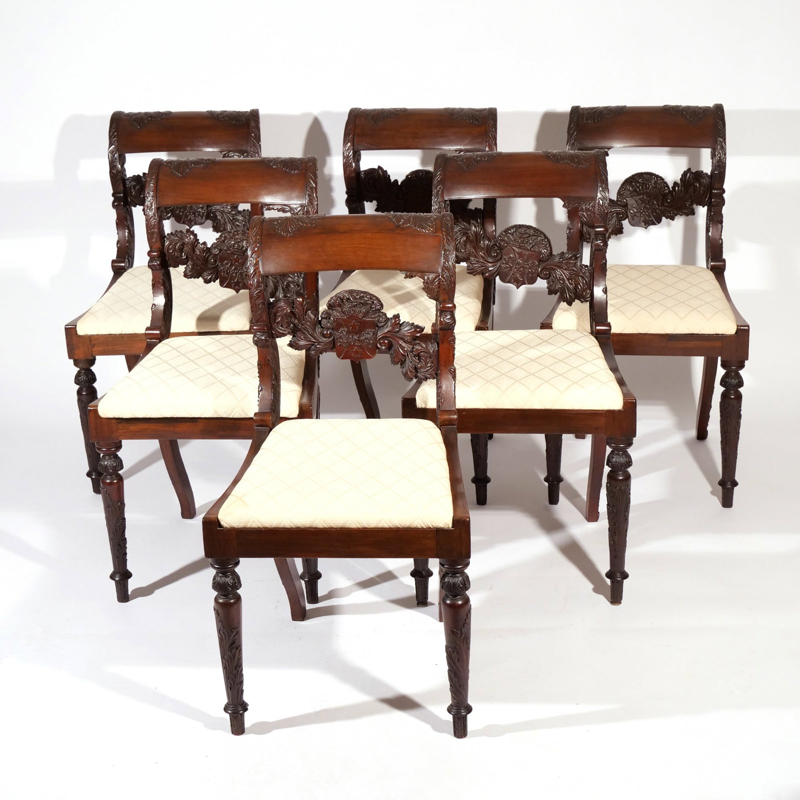 (6pc) REGENCY MAHOGANY ARMORIAL DINING CHAIRS: Early 19th century, possibly Irish, heavily carved with scrolling back and medial splats showing a coat of arms with two griffins flanking a lion rampant and stars above and below, joined by scrolling