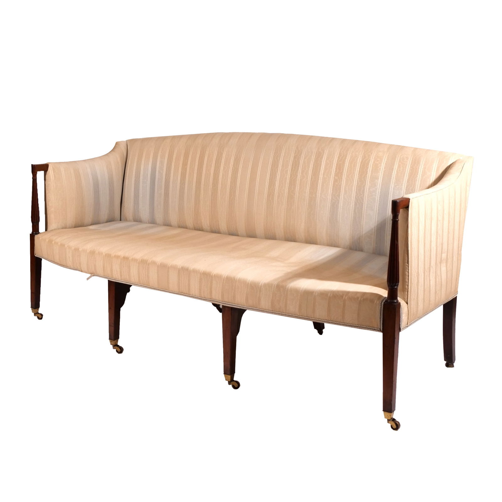 FEDERAL MAHOGANY SOFA: Late 18th century, having bowed crest rail over upholstered back rest and seat, exposed front turned reeded arm supports, resting on square tapering legs ending in brass spade shoes with casters; seat