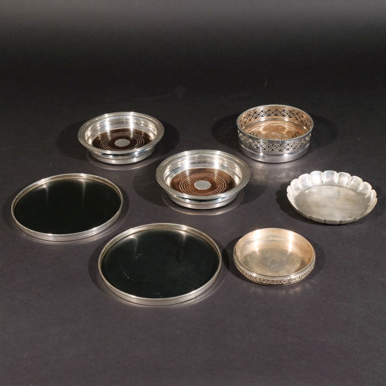 (7pc) STERLING & OTHER SILVER WINE COASTERS: Five sterling silver wine coasters, including a pair with wood bottoms, an Ensko Exemplar Paul de Lamerie coaster with scalloped rim, and a Gorham coaster with wood bottom; plus a pair of silver plate