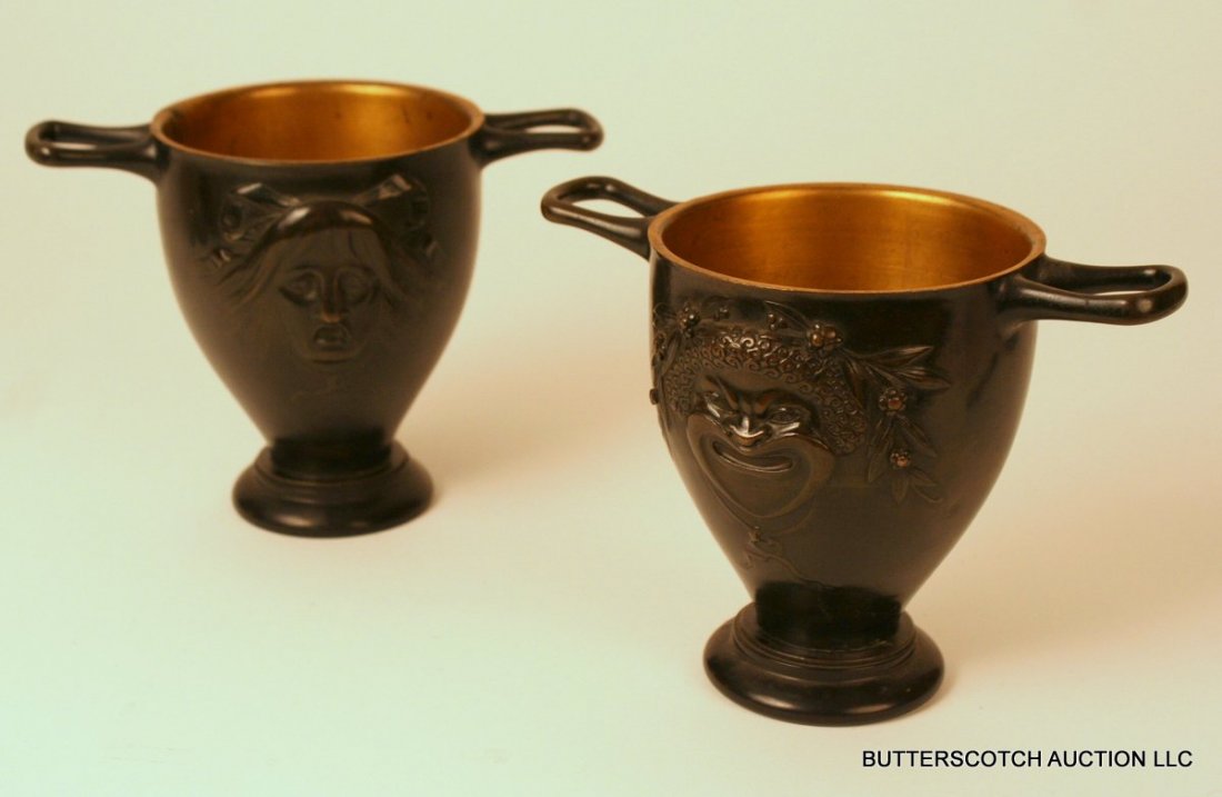 106) PAIR 19TH C. BRONZE LIBATION CUPS, AFTER THE: 106) PAIR 19TH C. BRONZE LIBATION CUPS, AFTER THE ANTIQUE, WITH A BACCHUS-LIKE FIGURE ON ONE SIDE AND A DISTRESSED FEMALE ON THE OTHER; BOTH ON A CIRCULAR BLACK MARBLE BASE; NO APPARENT MAKER'S MARK, 