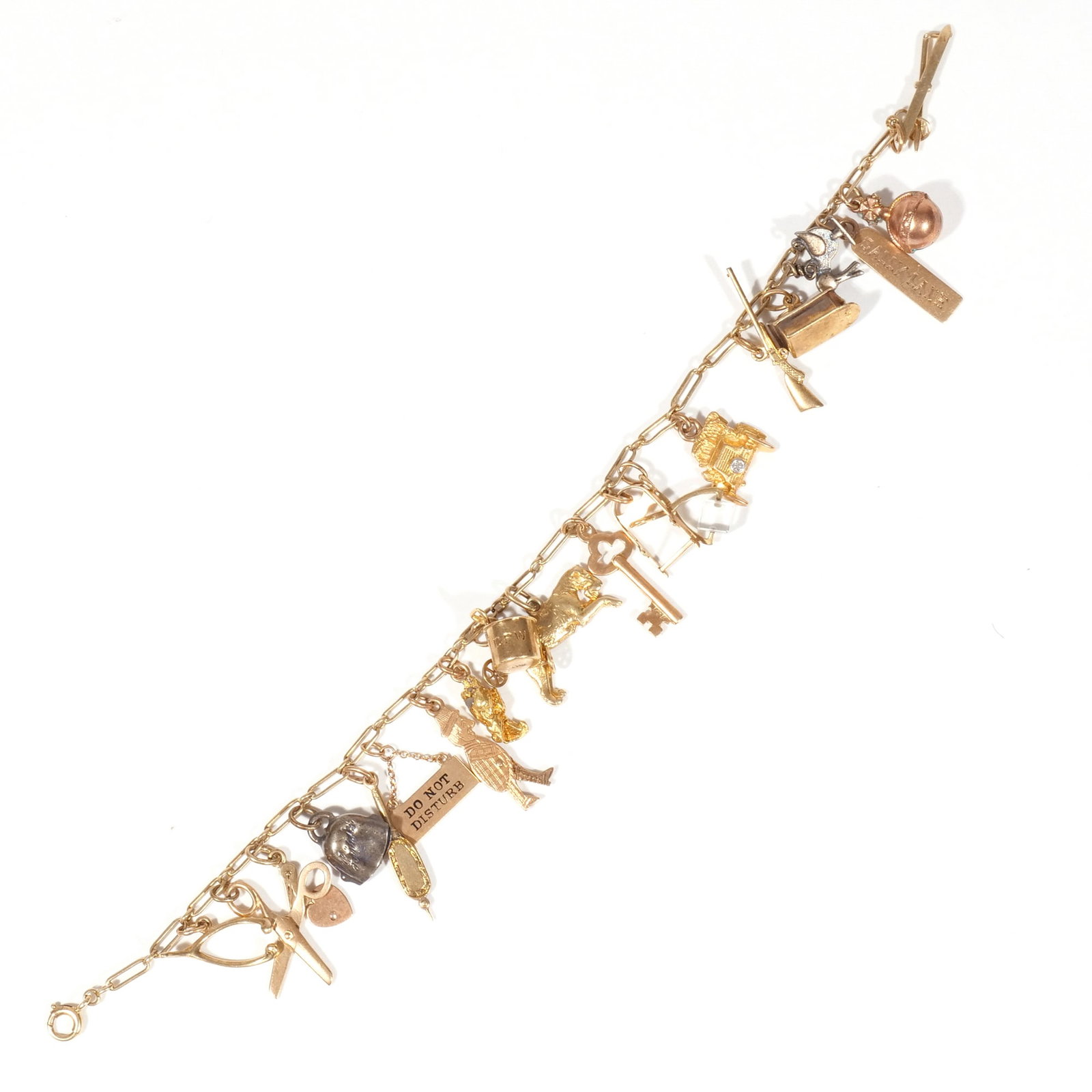 14k GOLD CHARM BRACELET: Yellow gold charm bracelet with several charms, including a scissor charm, a small key, an automobile, a rifle, a dog, a wishbone and more, most charms with fineness marks, bracelet tested to 14k; 21g