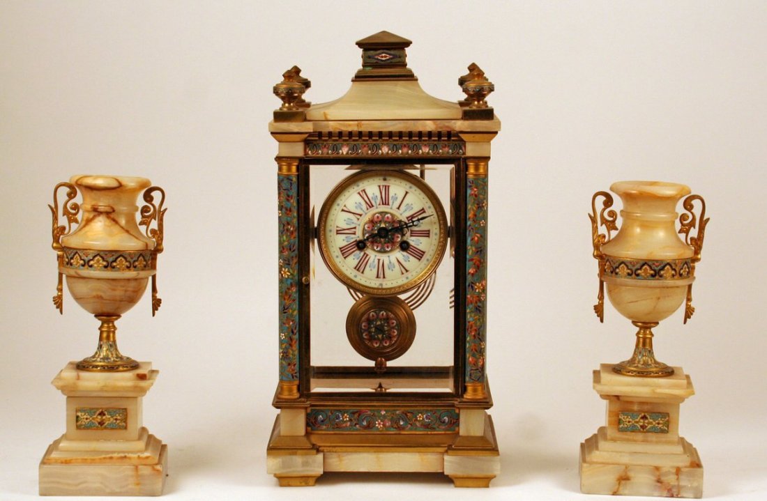 214) WHITE ONYX AND CHAMPLEVÉ CLOCK GARNITURE SET,: incl.: a mantle clock (H: 17") mkd. Paris, 1855, and a pair of urns (H: 12")