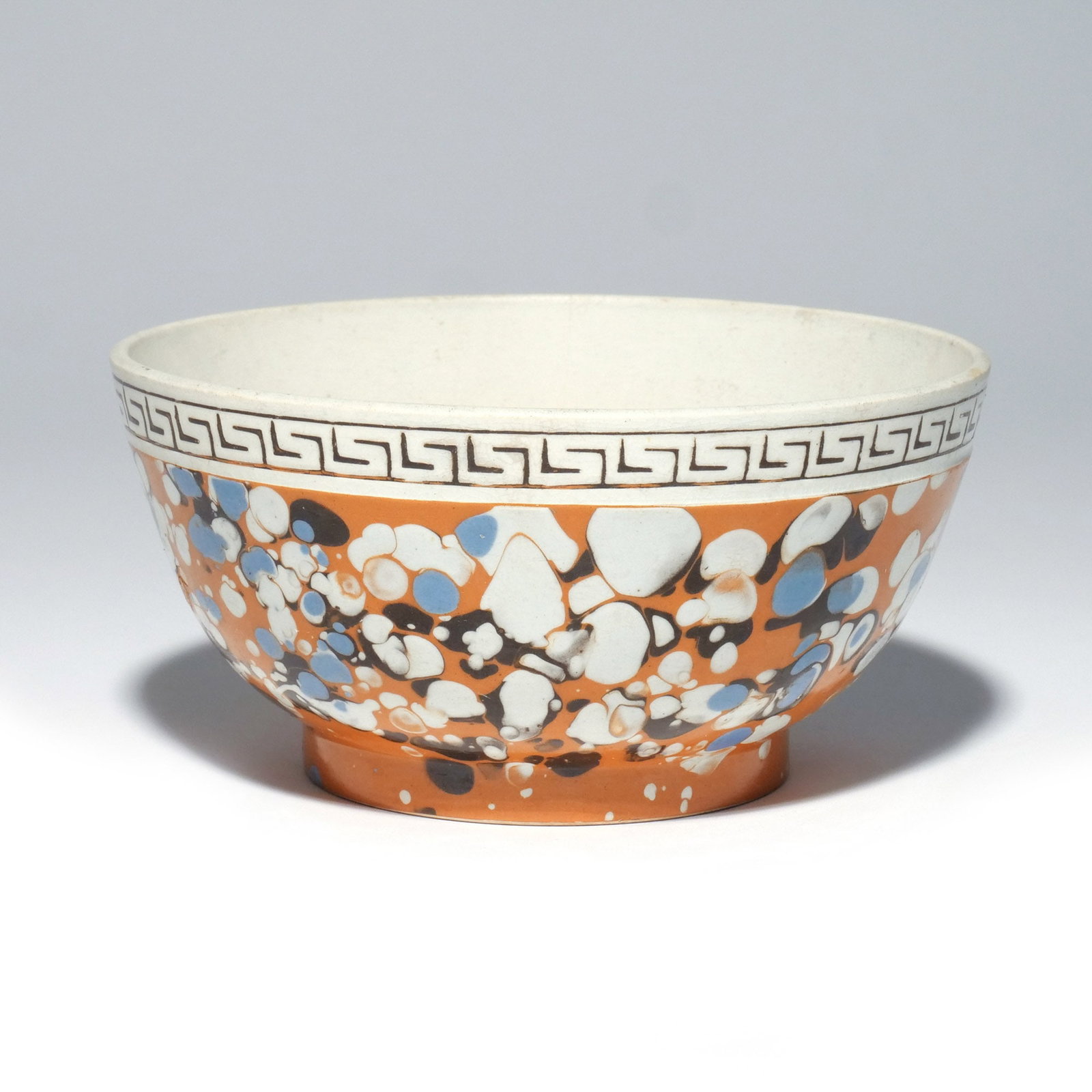 E. 19TH C. MOCHA SLIP DECORATED FOOTED BOWL: Having Greek key rim, over marbled slip decoration with ochre ground, h. 3 in. dia. 6-1/4 in. Provenance: Property of a Pound Ridge, NY gentleman