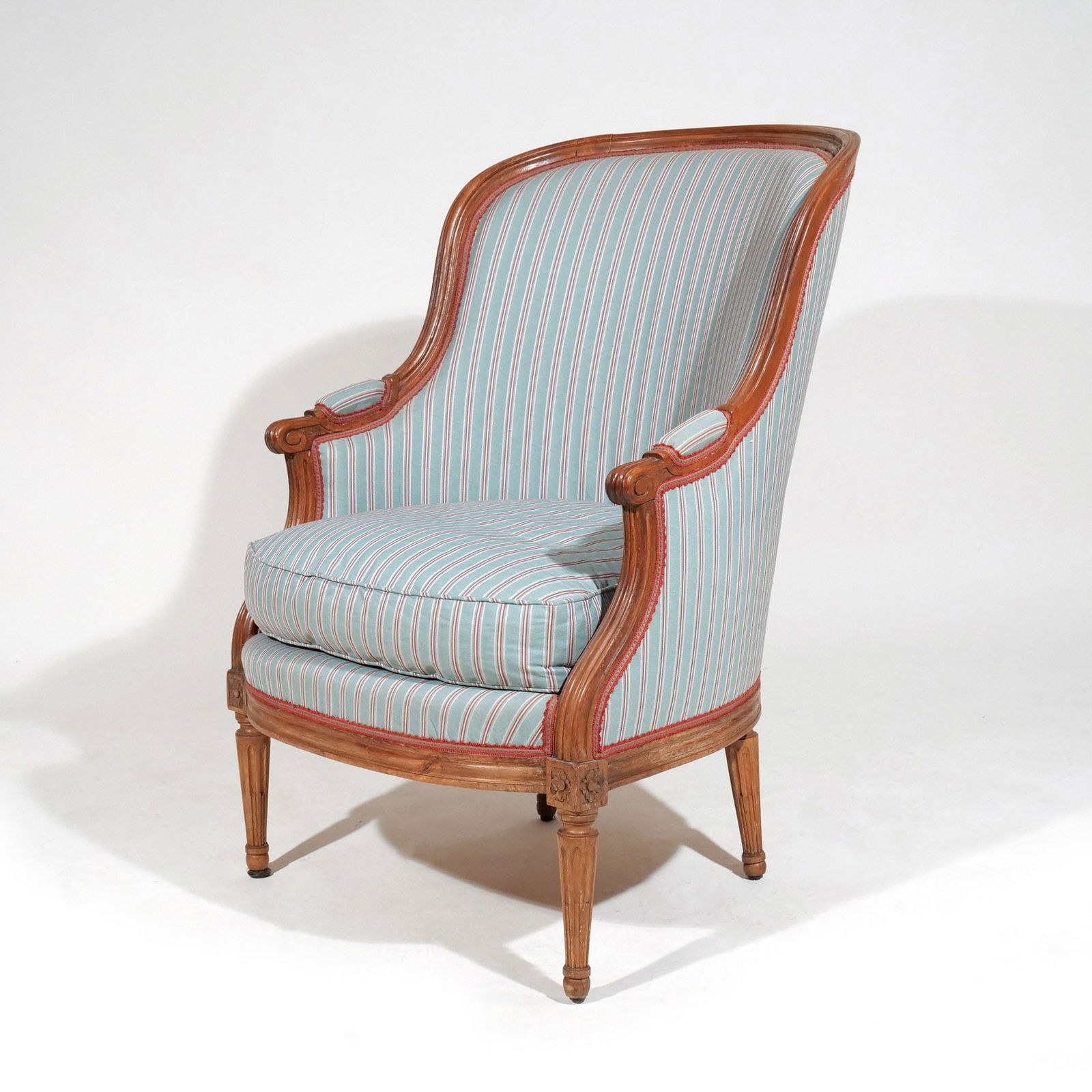 LOUIS XVI-STYLE BERGERE EN CABRIOLET: With striped upholstery and padded armrests, with matching loose cushion h. 36-1/2 w. 26-1/2 d. 29 in. Provenance: Descended through a Greenwich, CT family [In Situ Item] This item will not be on disp
