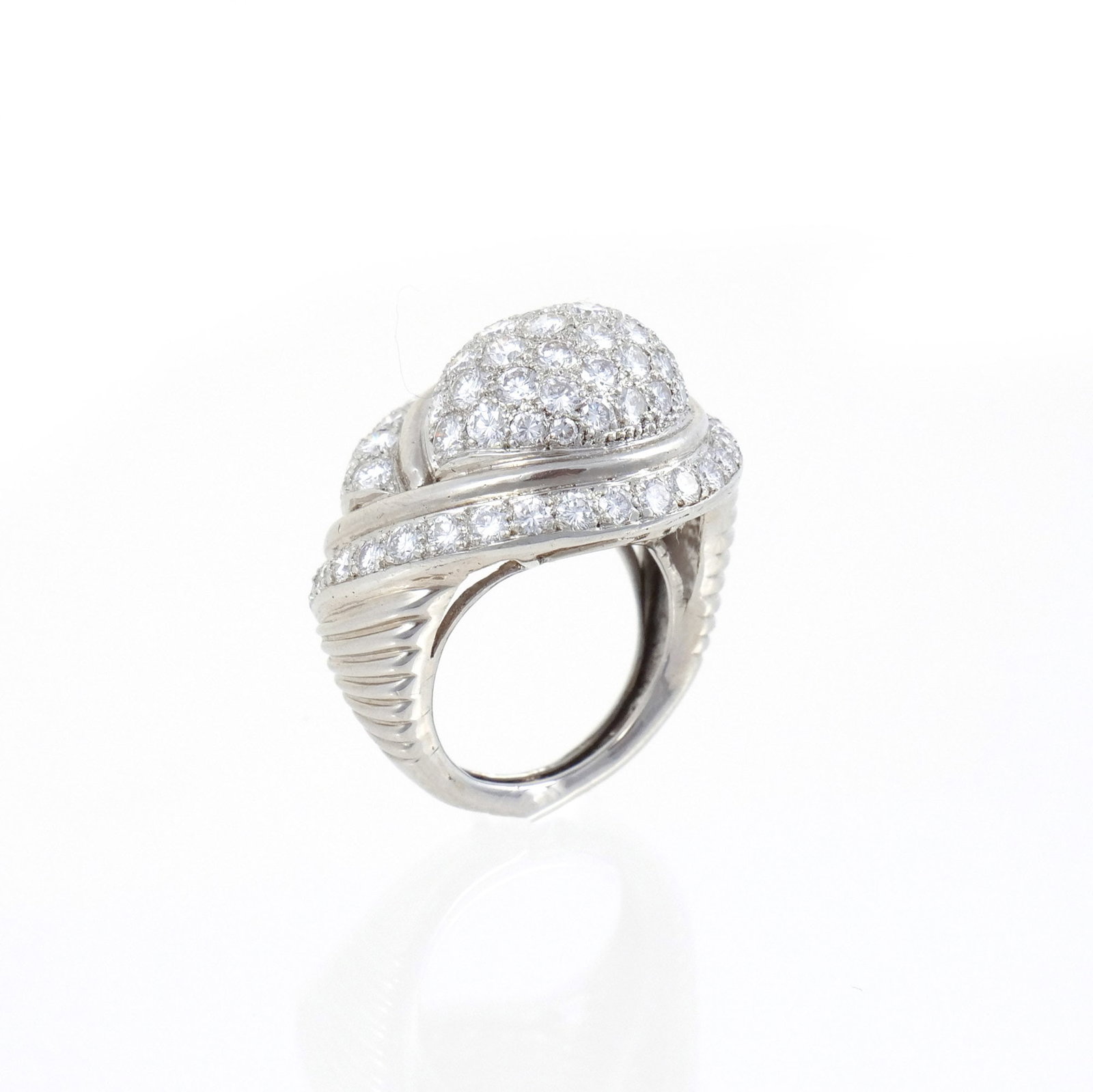 14K WHITE GOLD AND DIAMOND RING OF BOMBE SHAPE: Of swirl design, pave set throughout with round brilliant diamonds ranging in size from approx. 0.05 to .15 carats each, fluted shanks, unmarked but tests as 14k, w. 22 mm, size 6, 16 grams total weig