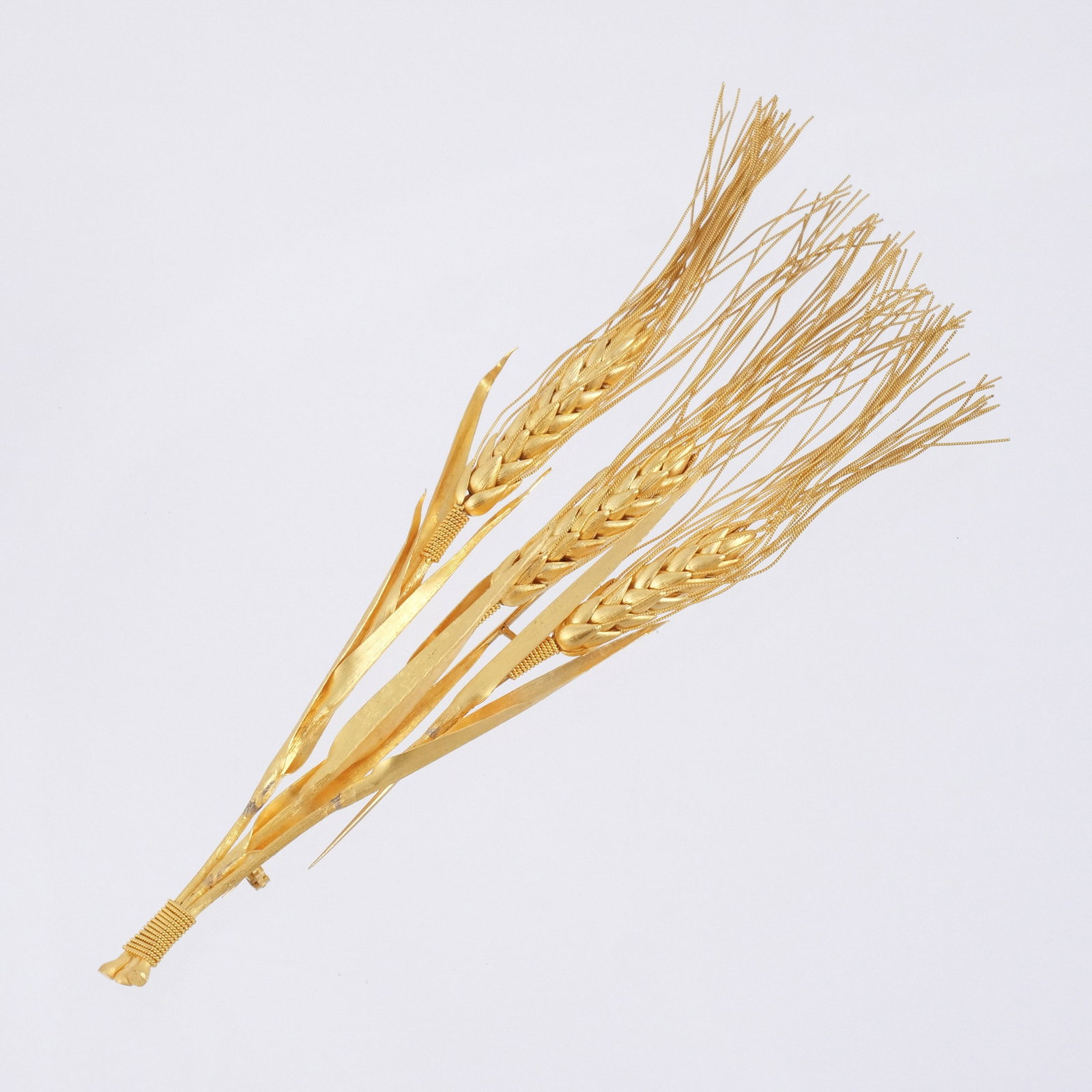 22K GOLD WHEAT STALKS BROOCH: Three bound stalks of textured and roped gold with soft twisted wire awns, stamped 'K22', l. 7 in., 41.8 g Provenance: Descent through a deceased former U.S. Ambassador's estate Wheat is a timeless