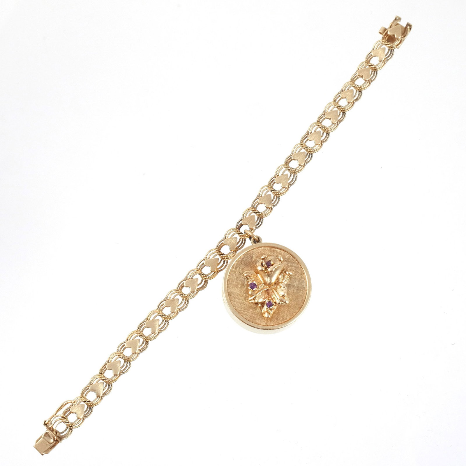 14K GOLD MUSIC BOX BRACELET: Circular case with textured gold ground and applied floral motif set with small amethysts housing a mechanical music box movement with pinned cylinder and comb, integrated winding mechanism, suspended