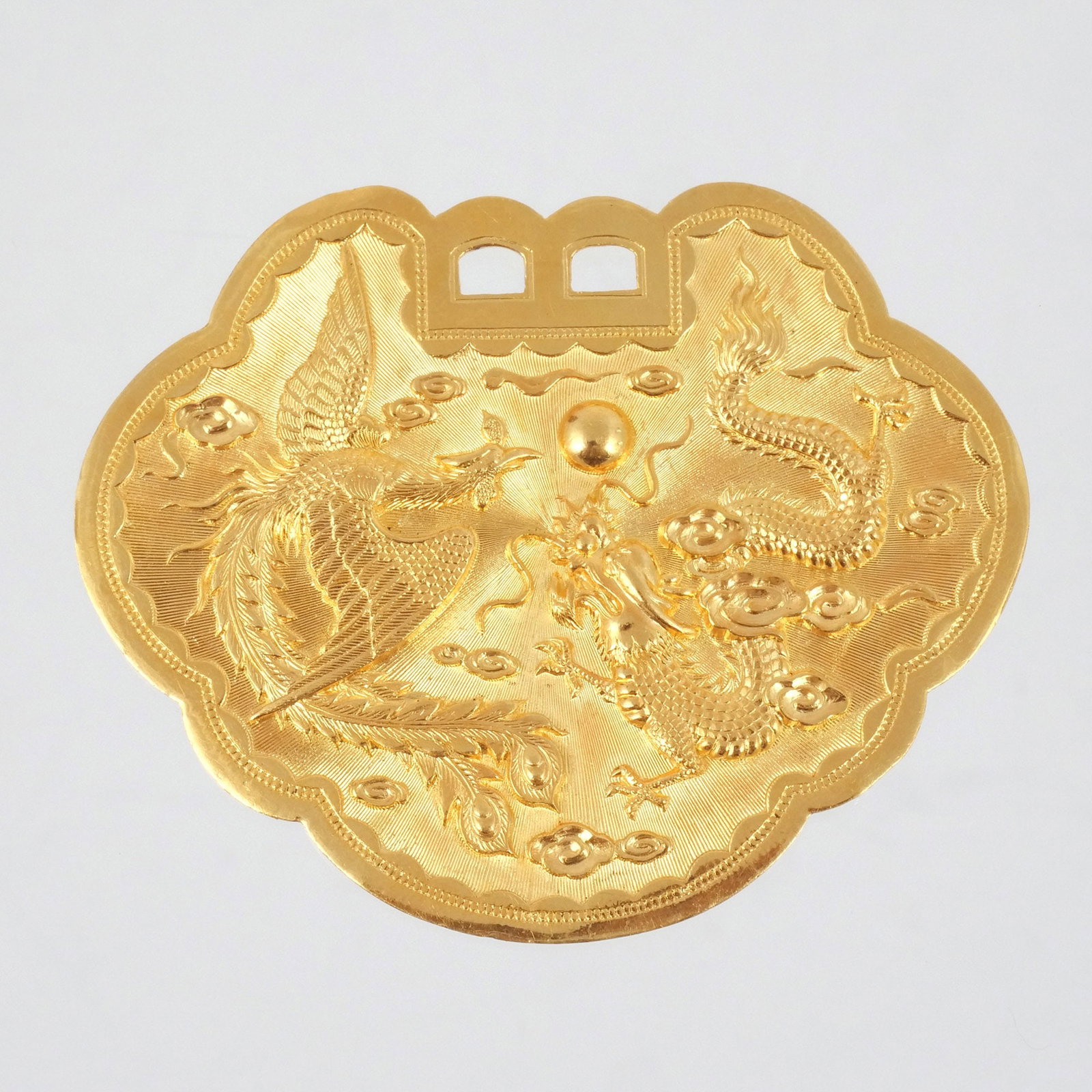 CHINESE 24K GOLD RUYI-FORM PENDANT: Engraved with a phoenix and dragon chasing a pearl among clouds, with Chinese hallmarks 'jin zu zheng bao' (for .999 gold) and 'Da yue' (?, partially obscured), 37.2 g h. 2-3/8 w. 2-7/8 in. Provenance