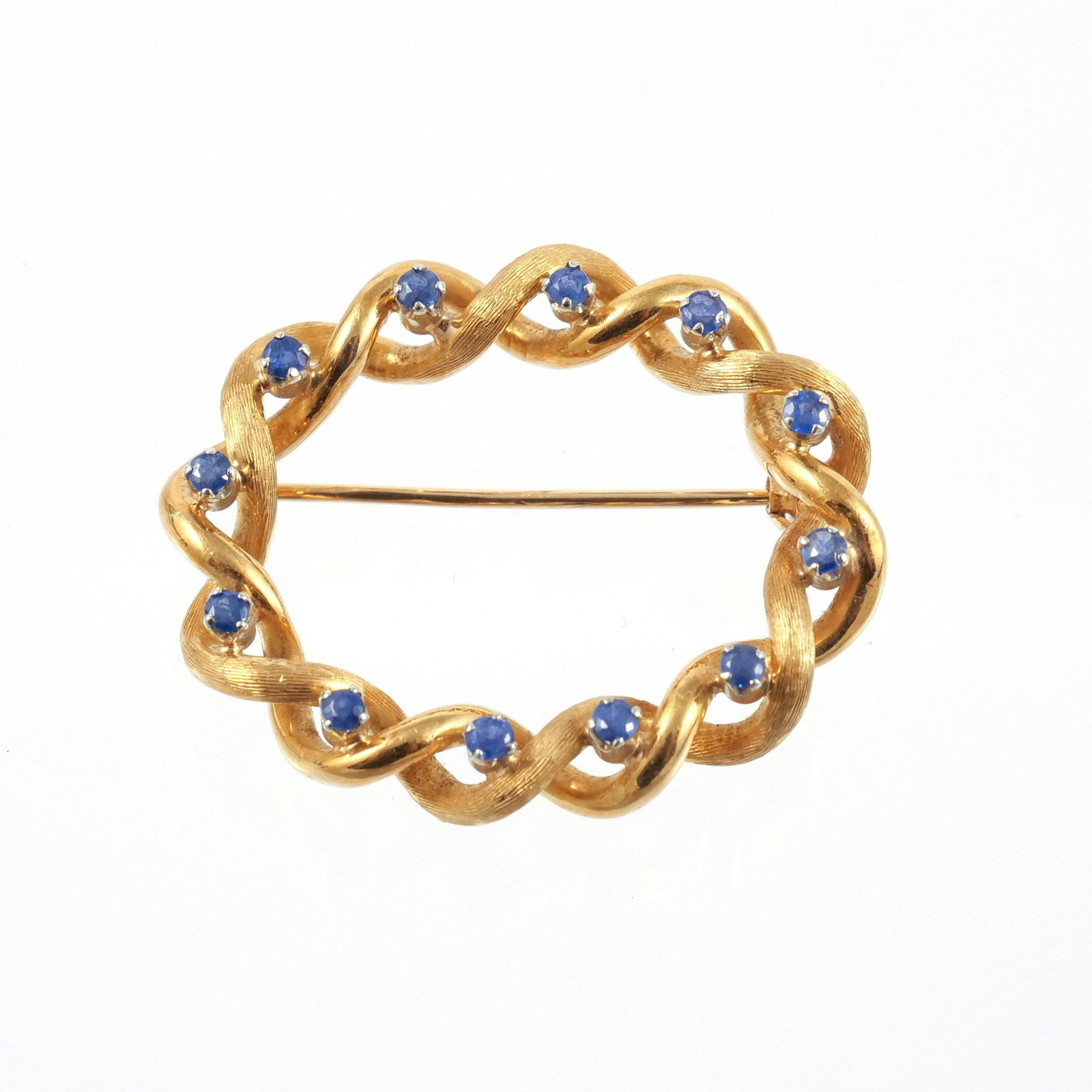 TIFFANY & CO. 18K ITALIAN GOLD AND SAPPHIRE BROOCH: Twisted rope-form of textured and polished gold with high set sapphires, approx 0.6 cts total weight, signed 'Tiffany & Co.' and marked 'Italy / 18k', 6.2 g total weight h. 1-1/8 w. 1-3/8 in. Provenan