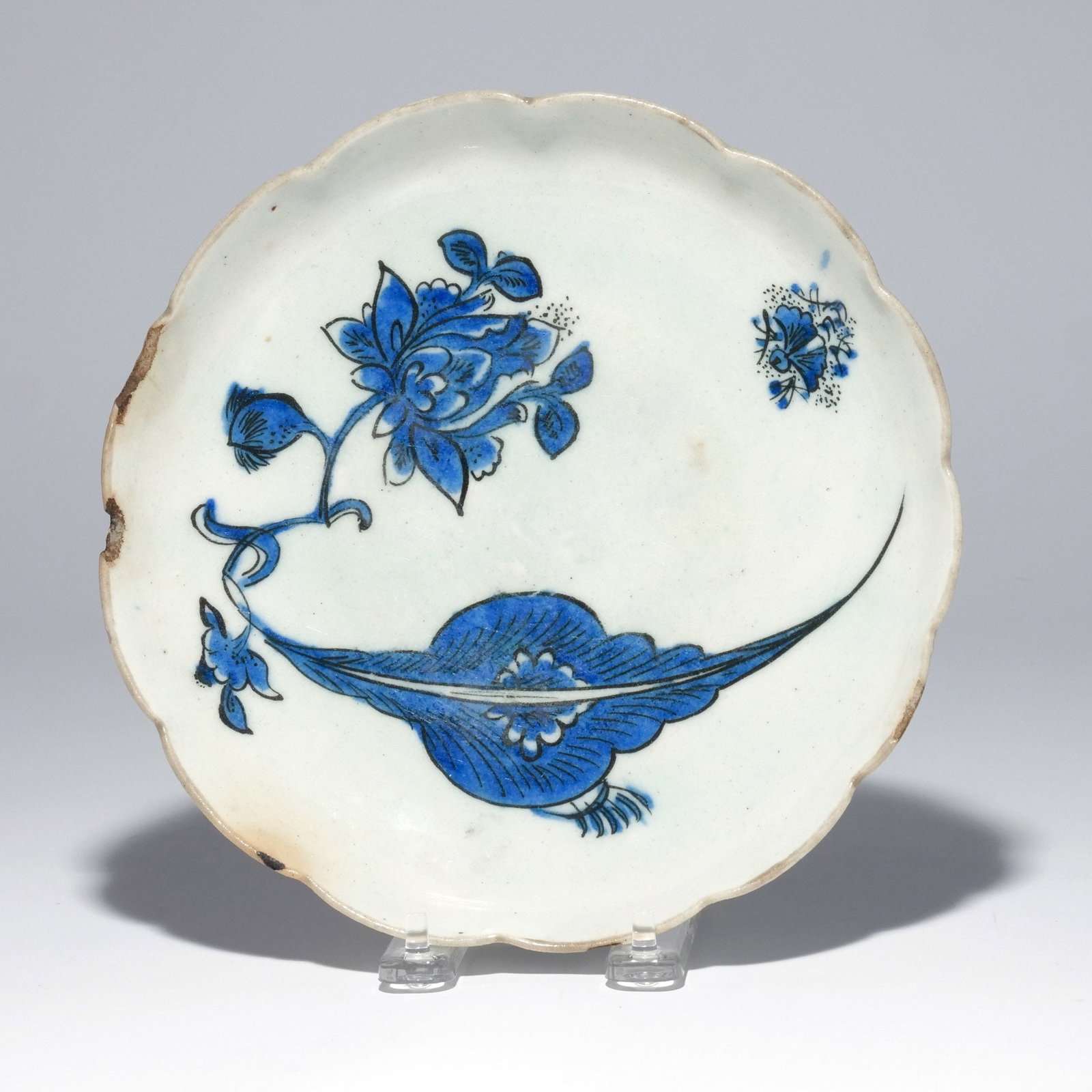 SAFAVID BLUE & WHITE SCALLOPED 'FIREFLY' DISH: Probably Kerman, Iran, C. 1650-1680, having lobed 'chrysanthemum' shape rim, shallow rounded bowl with slightly tapering foot, interior decorated with a large curved leaf, a lotus spray, and a firefly