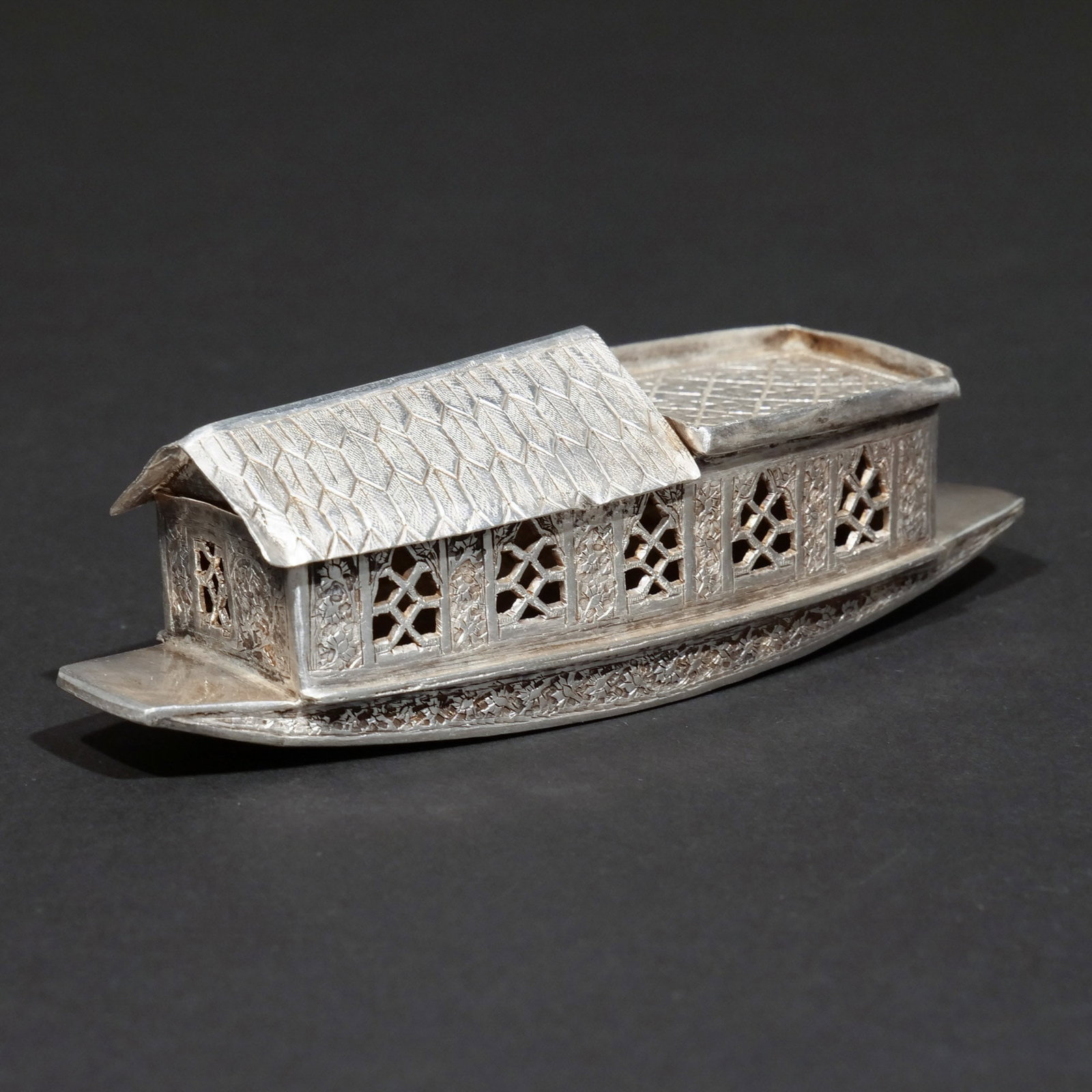INDIAN SILVER SHIKARA BOAT: Probably Kashmir, circa 1910, with a poppy pattern on the sides and lattice patterns adorning the two roofs, no apparent hallmarks; 2.7 ozt h. 1-1/2 w. 5 d. 1-1/2 in. Provenance: Descended through the