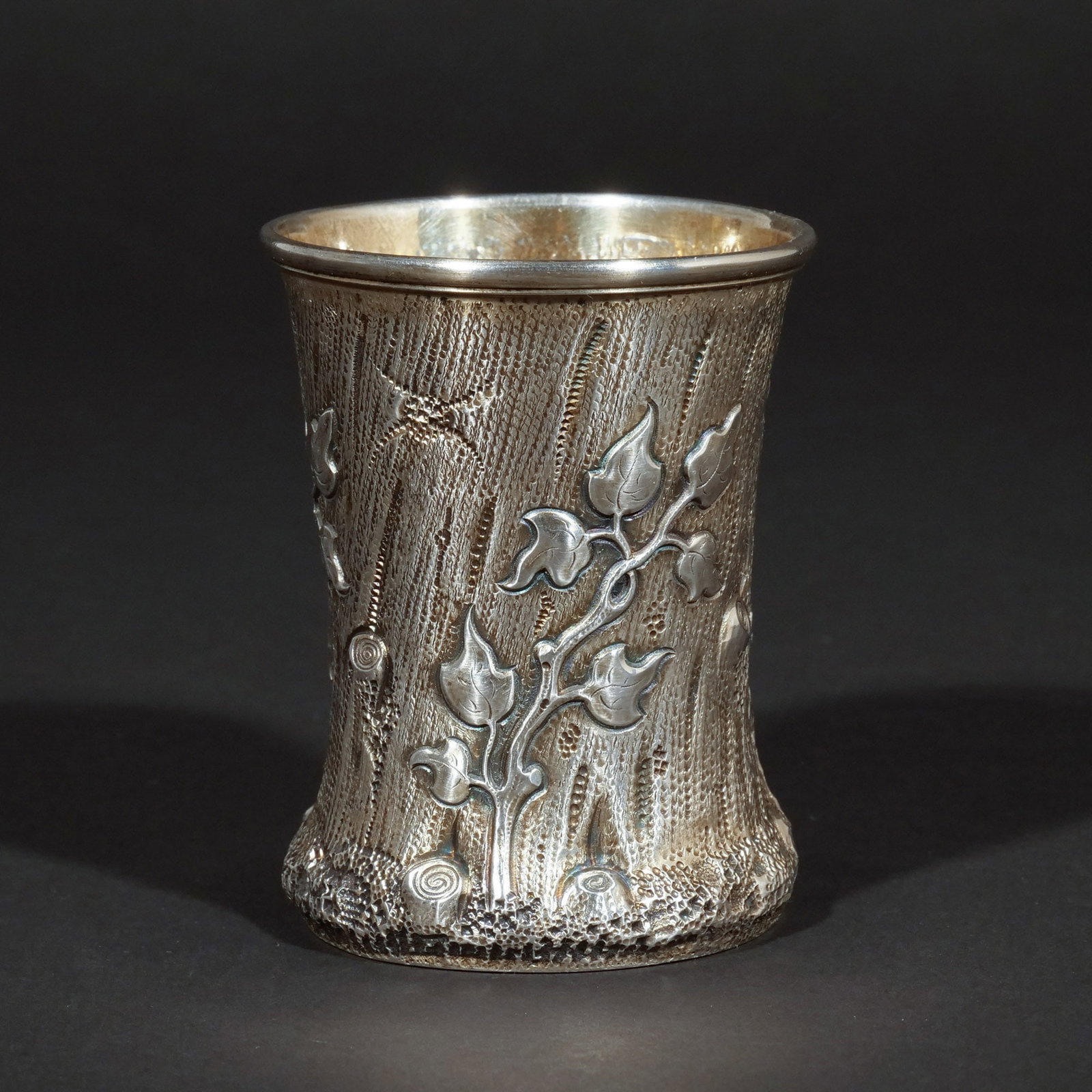 RUSSIAN '84' SILVER BEAKER IN REPOUSSE: Moscow, circa 1852, having leaf decoration on a stippled tree-bark ground, interior with gilt, stamped '84', with 'H.A. 1852' assay mark, Moscow hallmark, and maker's mark 'BII'; 3.59 ozt h. 3-3/8