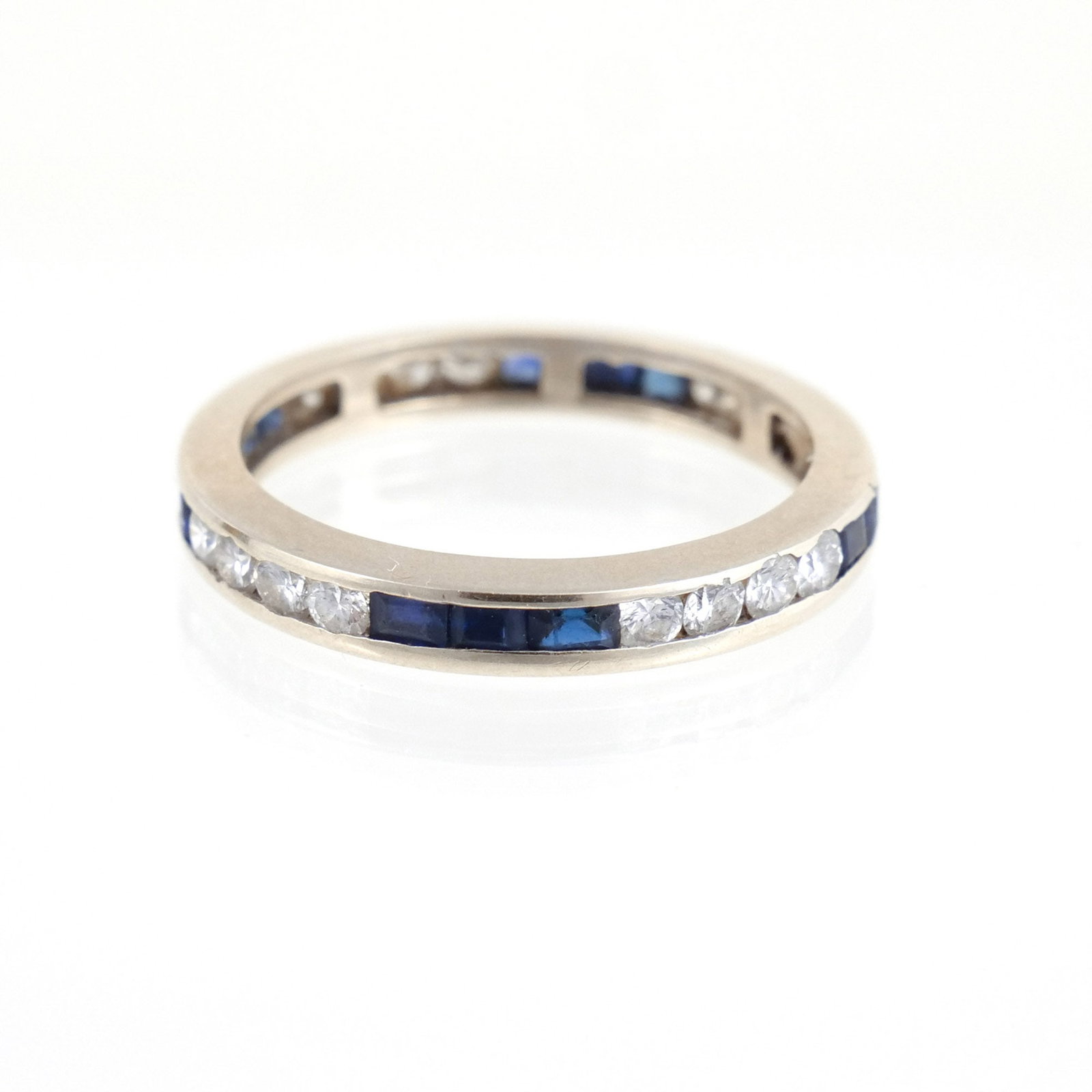 PLATINUM, DIAMOND, AND SAPPHIRE ETERNITY BAND: With 13 square-shaped channel set sapphires and 16 round melee diamonds, size 6-1/4, no fineness mark Provenance: Descent through a prominent Greenwich, CT family