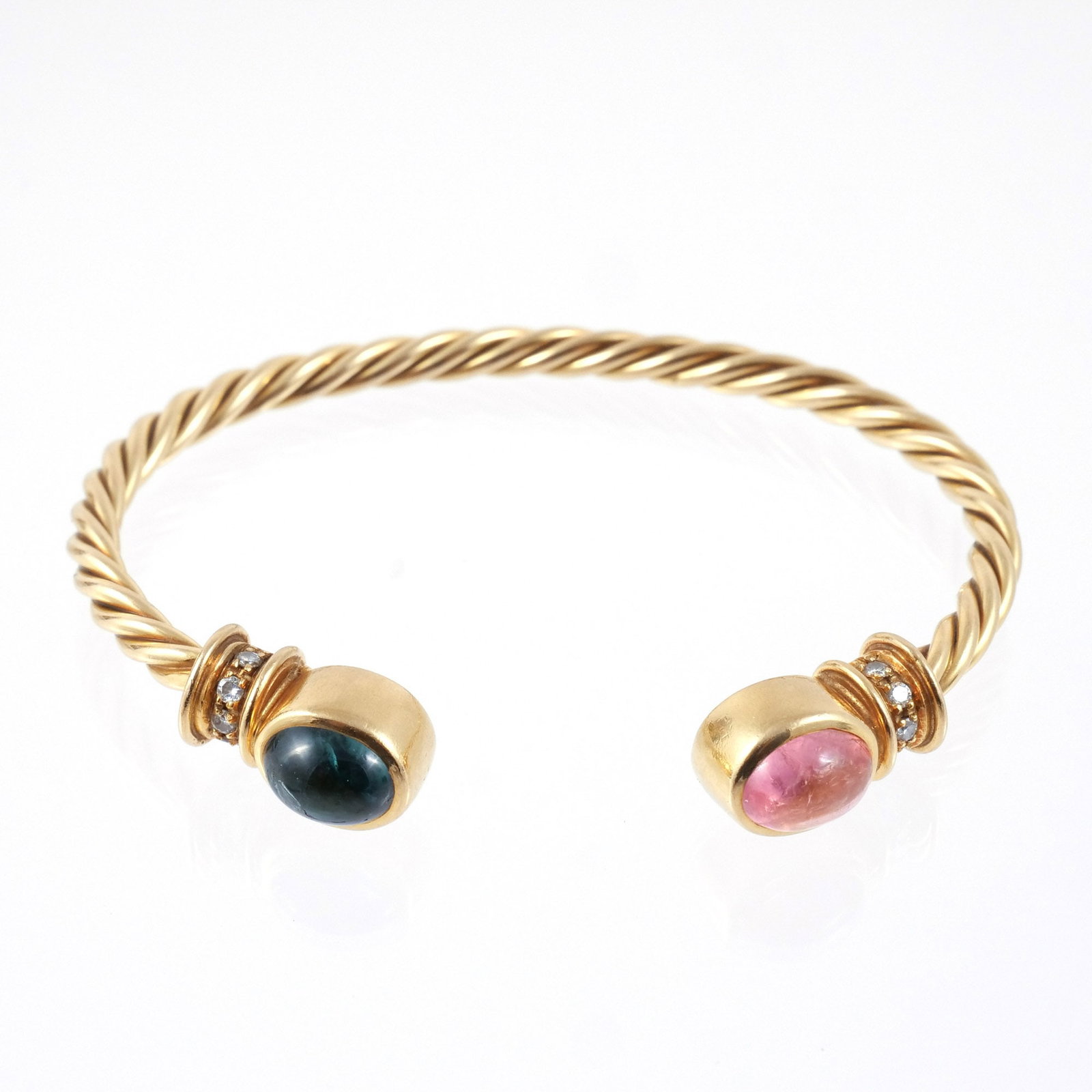 18K GOLD TWISTED ROPE TORQUE BANGLE: In the style of Bulgari, with green and rose colored cabochon gemstone terminals and diamond-inset collars, marked '750', 6-1/2 in. interior circumference, 29 g total weight