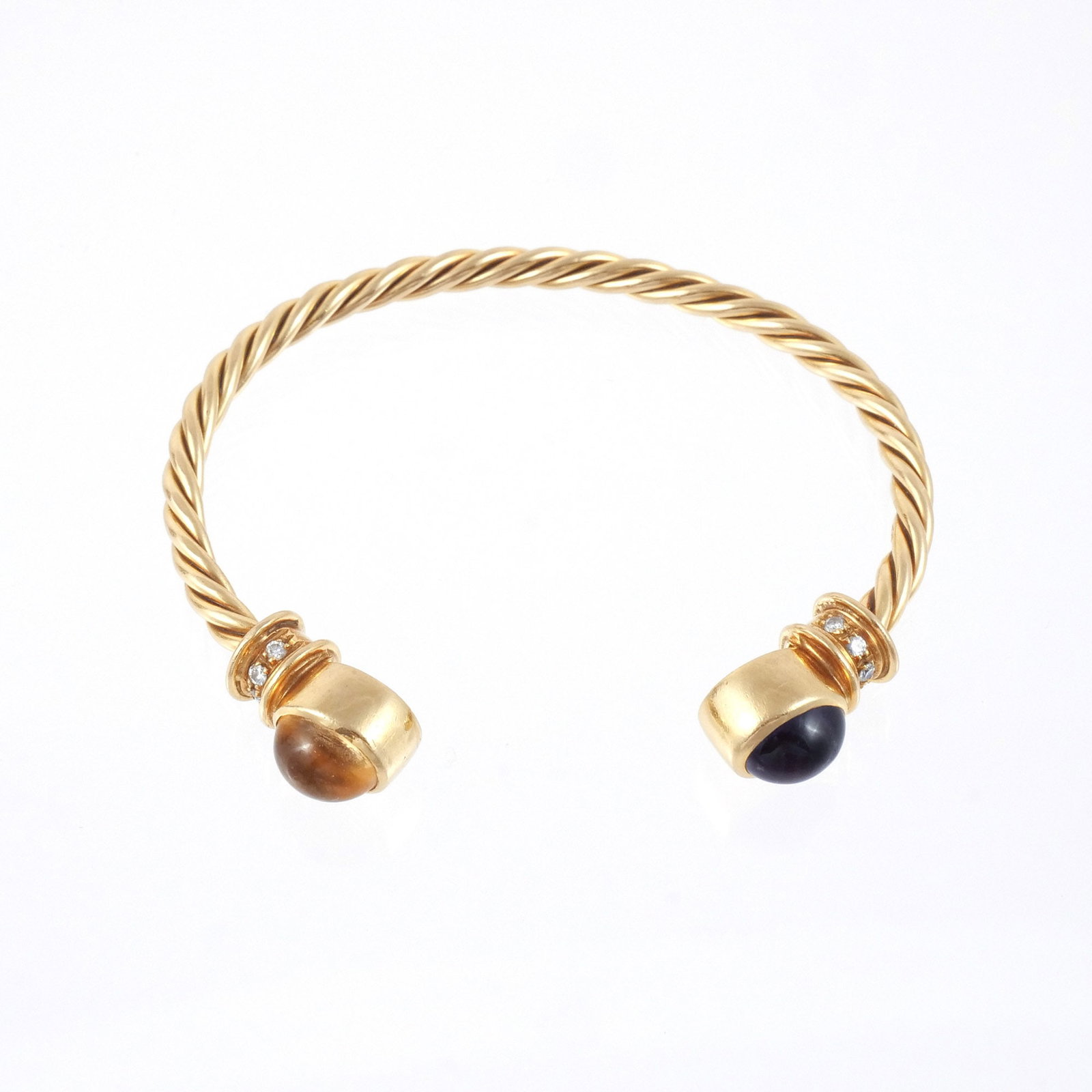 18K GOLD TWISTED ROPE TORQUE BANGLE: In the style of Bulgari, with purple and yellow colored cabochon gemstone terminals and diamond-inset collars, marked '750', 6-1/2 in. interior circumference, 29 g total weight