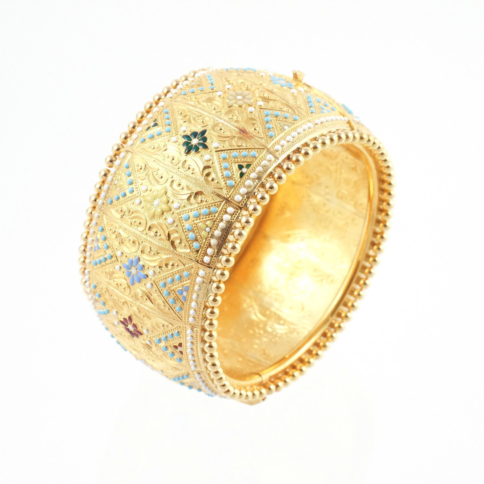 18K INDIAN GOLD and ENAMEL HINGED BANGLE: With a multicolor floral and filigree motif with a border of raised bosses, unmarked but tests as 18k, interior circumference 6-1/4 in., 66 g w. 1-3/8 in. Provenance: Descended through the family of
