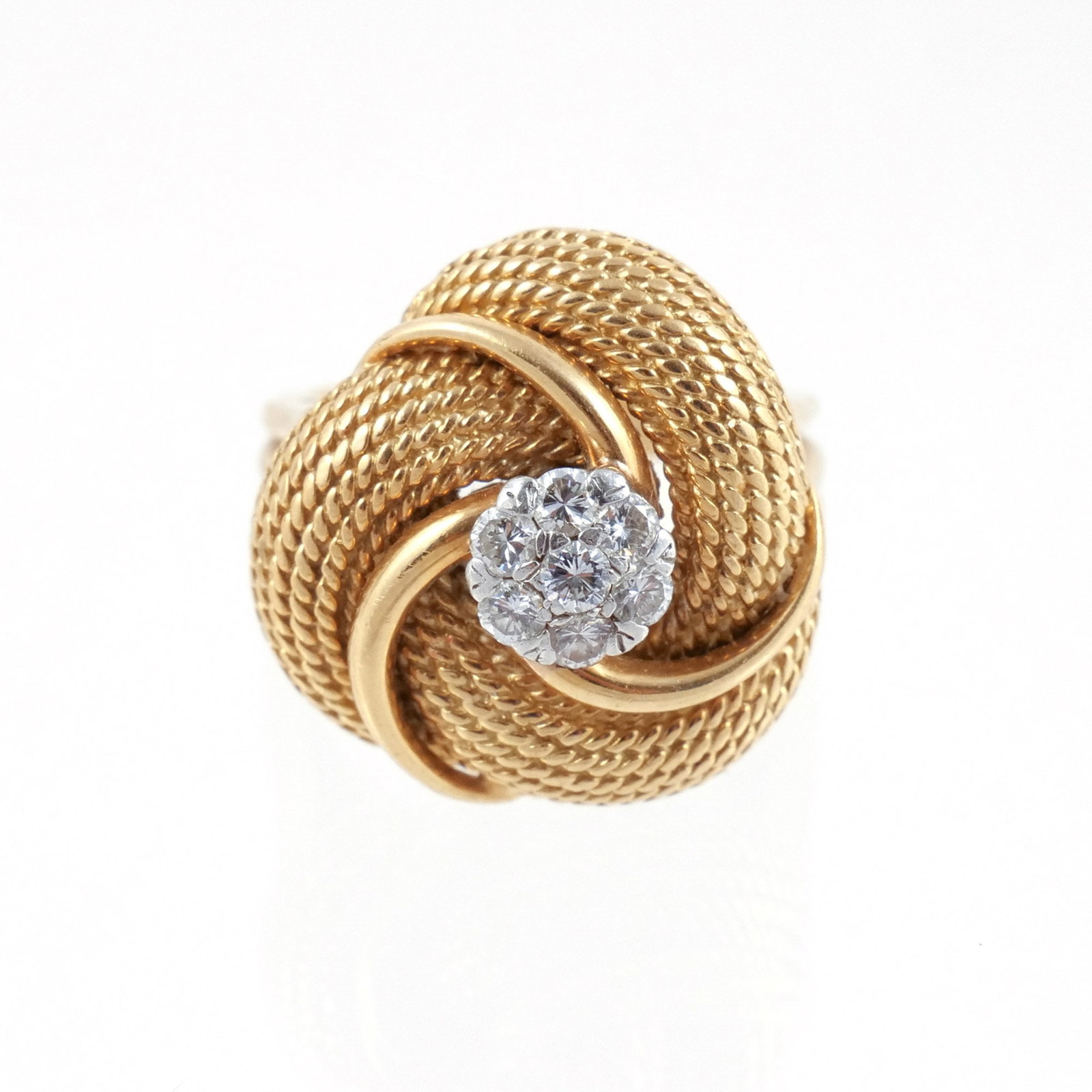 18K GOLD CONTINUOUS KNOT DIAMOND CLUSTER RING: Of bombe-form, designed as a swirling knot of gold rope interwoven with polished gold and mounted with 7 full cut diamond each approx. .05-.07 cts, signed 'FAVA' and marked '18k', size 6-1/2, 15.6 g