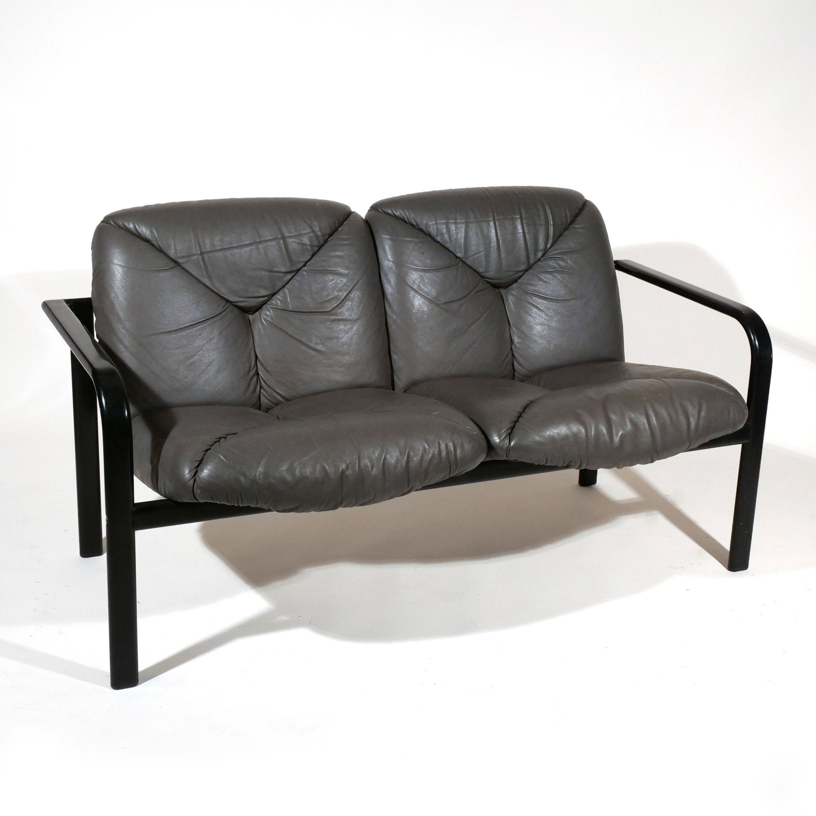 VICO MAGISTRETTI for ICF SETTEE: Circa 1980s, black-painted steel with two-cushion black leather upholstery, ICF label on bottom h. 30 w. 55 d. 29 in. Provenance: The estate of Richard and Jean M. Bergstresser, owner of the Laurence