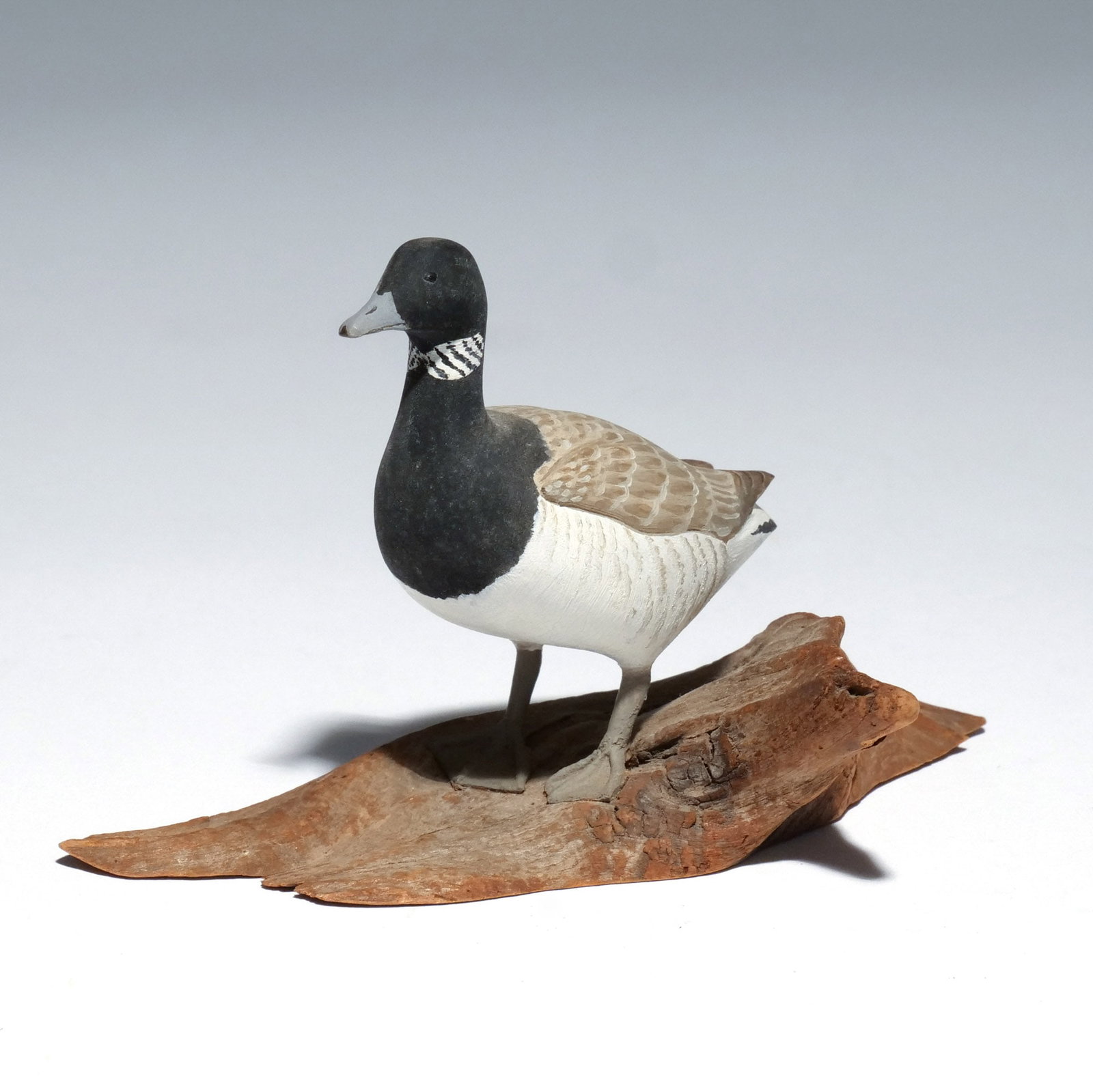HAROLD GIBBS (1886-1970) ATLANTIC BRANT: Carved miniature, mounted on a driftwood base, signed with conjoined 'HNG' on underside h. 2-7/8 w. 4-7/8 d. 2-1/2 in. (overall) Provenance: Descended through the estate of U.S. Ambassador James C. H.