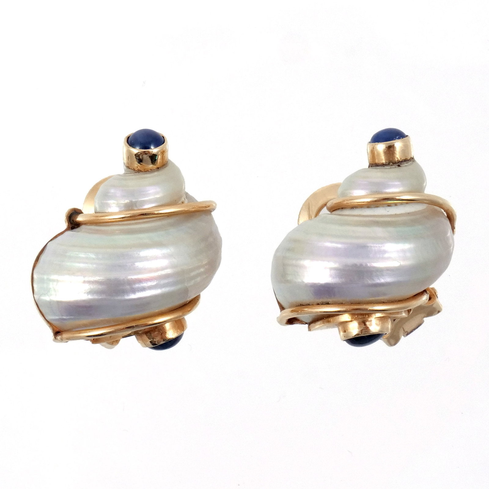 PAIR SEAMAN SCHEPPS 14K GOLD TURBO SHELL EAR CLIPS: With 14k gold accents and cabochon sapphire terminals, signed 'P.S.V. of Seaman Schepps' for Patricia Schepps Vail and marked '14k', 15.4 g total weight h. 1 in. Provenance: Descended through the esta