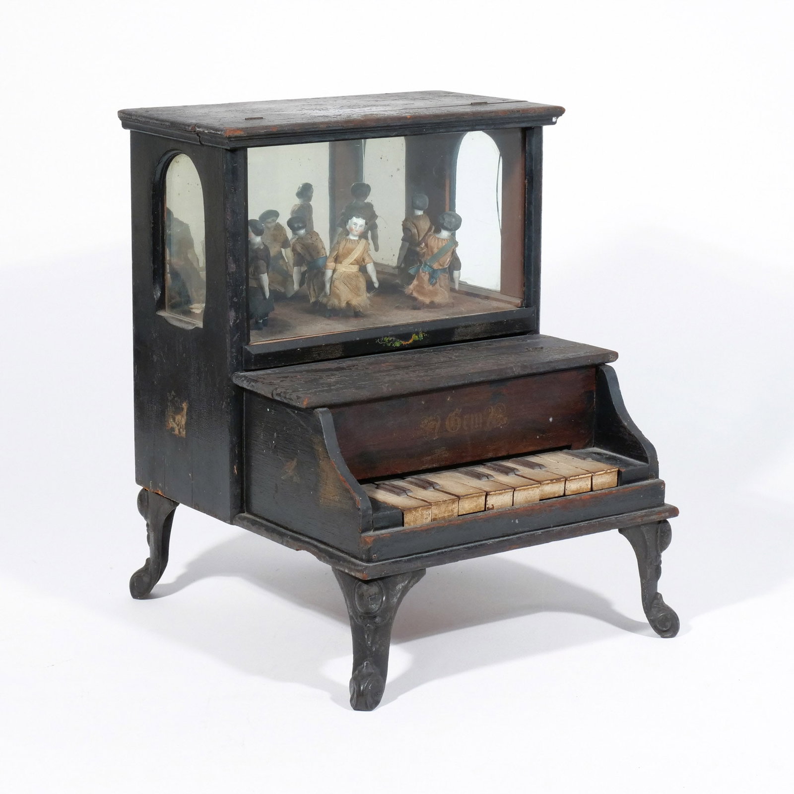 BAILEY'S MIDGET PIANO: Patented June 21, 1881, wooden piano with ornate cast iron legs; 4 of the 6 keys activate one of the cloth-dressed china dolls, with mirrored back giving the illusion of 8 dancers in all h. 13-3/4 w. 