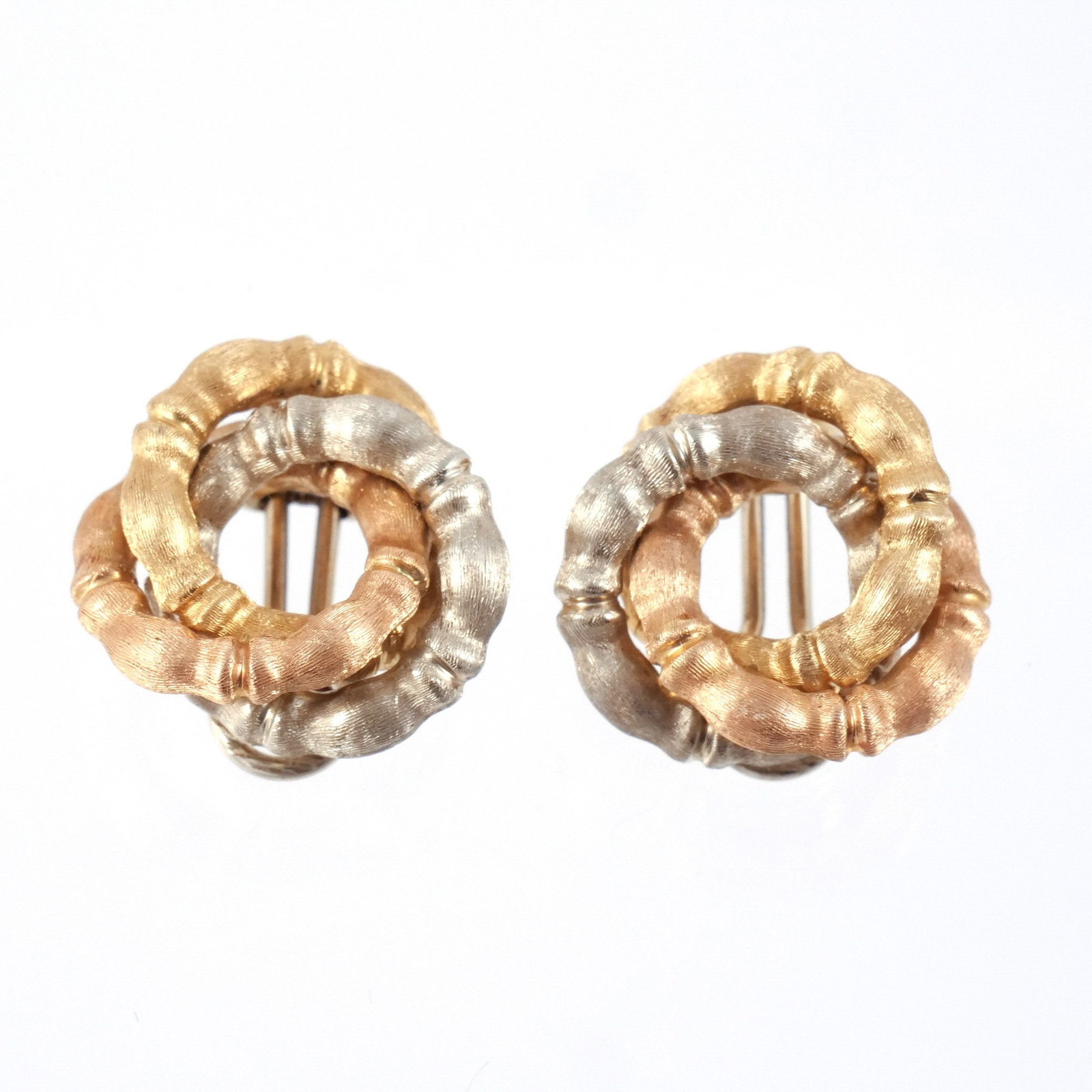 PAIR 18K TRICOLOR GOLD EAR CLIPS: Composed of three interlocking textured bamboo-form rings in yellow, white, and rose gold, marked '750' with possible maker's mark, 12.5 g total weight dia. 7/8 in. Provenance: The estate of a noted a