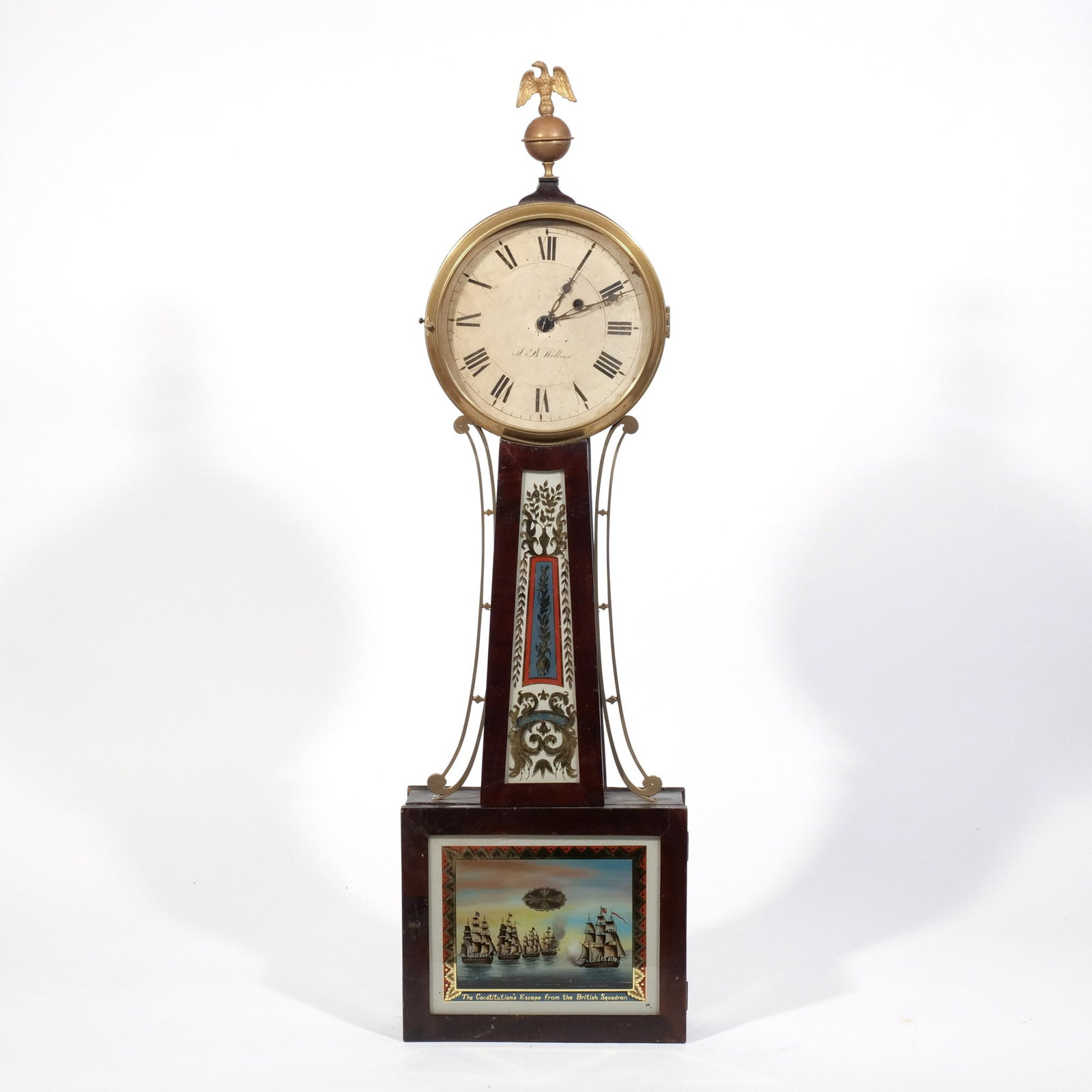 JOB WILBOUR BANJO CLOCK: Rhode Island, 19th century, the face signed 'J.B. Wilbour', as well as the eglomise panel at the neck, with repainted lower eglomise panel titled 'The Constitution's Escape from the British Squadron',