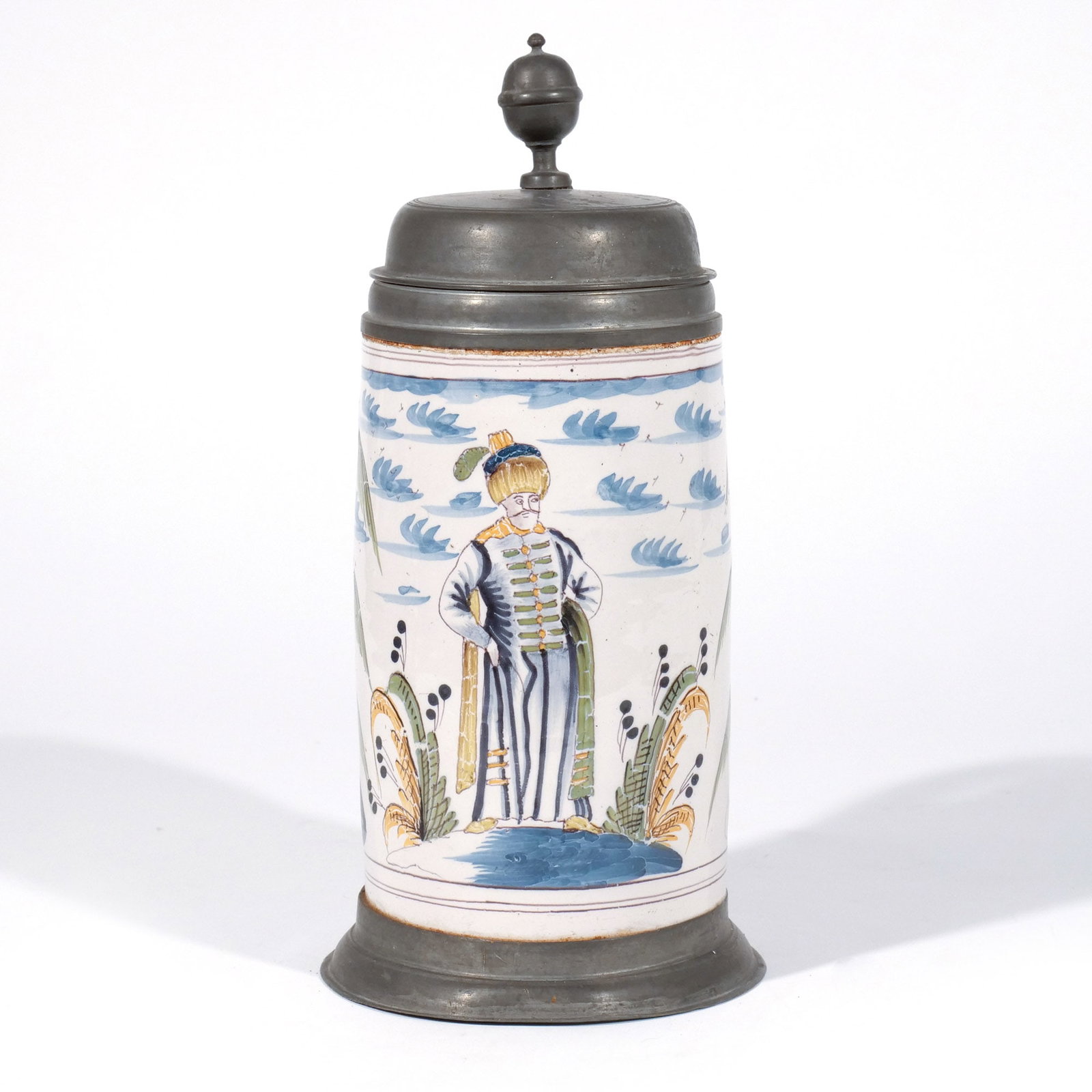GERMAN FAIENCE WALZENKRUG STEIN w. TURBANED FIGURE: Likely Augsburg, 18th century, decorated with a turbaned figure and palm trees, with pewter cover and base h. 11 in. Provenance: The estate of a noted architect and bibliophile, Rye, NY
