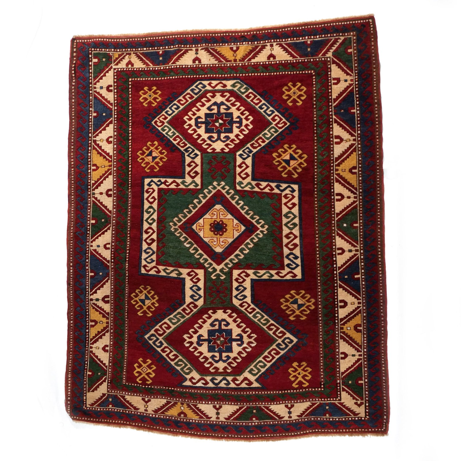 LORI PAMBAK or SEWAN KAZAK RUG: 20th century, with a stepped shield-like device on a madder red ground surrounded by meander-vine borders in white and other colors h. 7 ft. 1 in. w. 5 ft. 8 in. Provenance: Private collection,