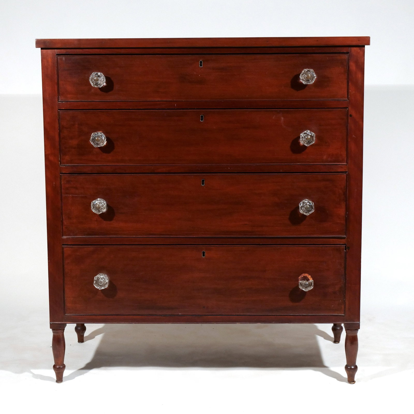 LATE FEDERAL CHERRYWOOD FOUR DRAWER CHEST: Having 4 cock beaded graduated drawers with locks, resting on round bulbous legs with peg feet, retaining original glass pulls h. 44-1/2 w. 41 d. 20 in. Provenance: Descent through a prominent