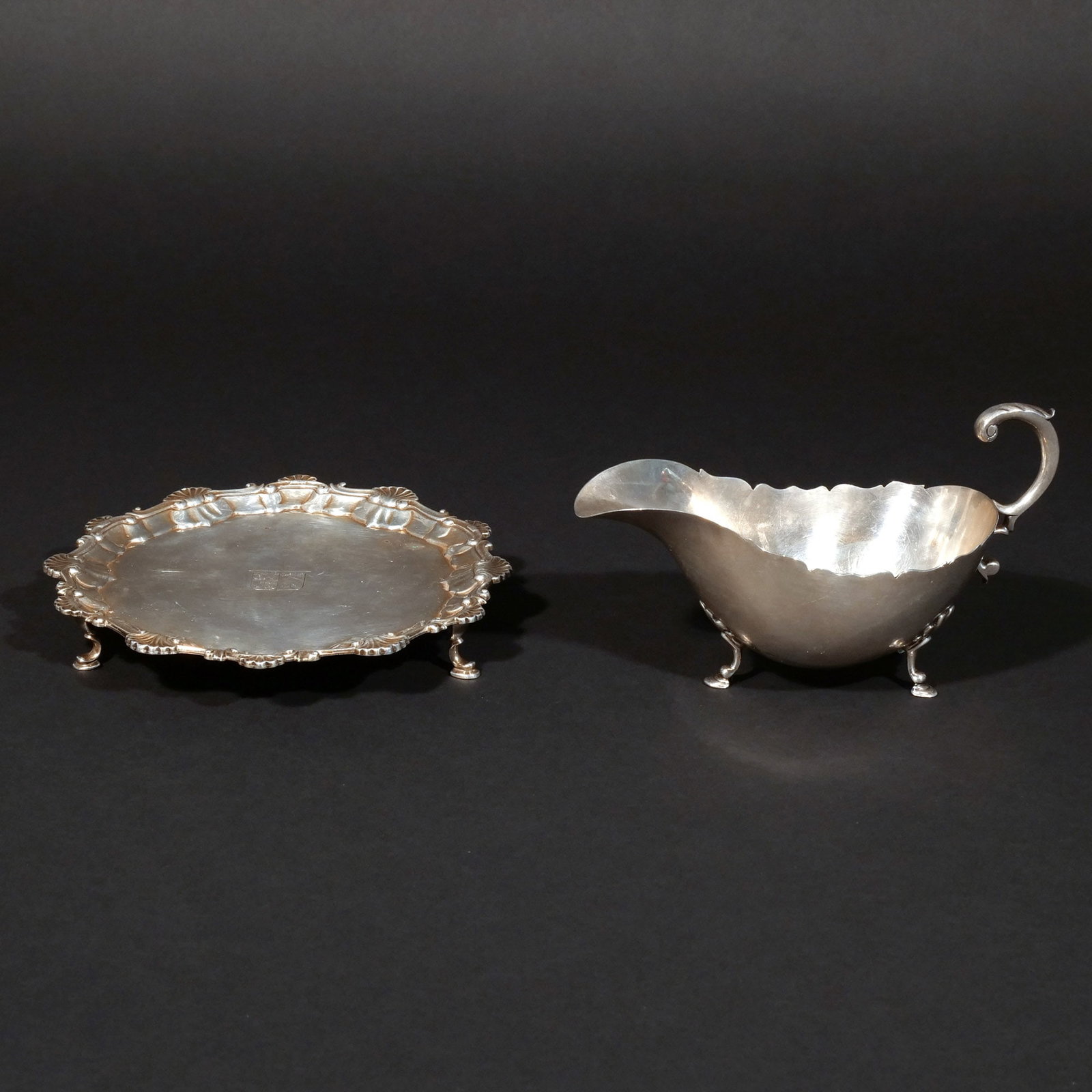 (2pc) STERLING SILVER HOLLOWARE: Including an English sterling silver waiter with engraved coat of arms and an American sterling silver gravy boat; 16 ozt total weight h. 4-1/4 w. 7-1/2 in. (gravy boat) dia. 7-1/2 in. (waiter)