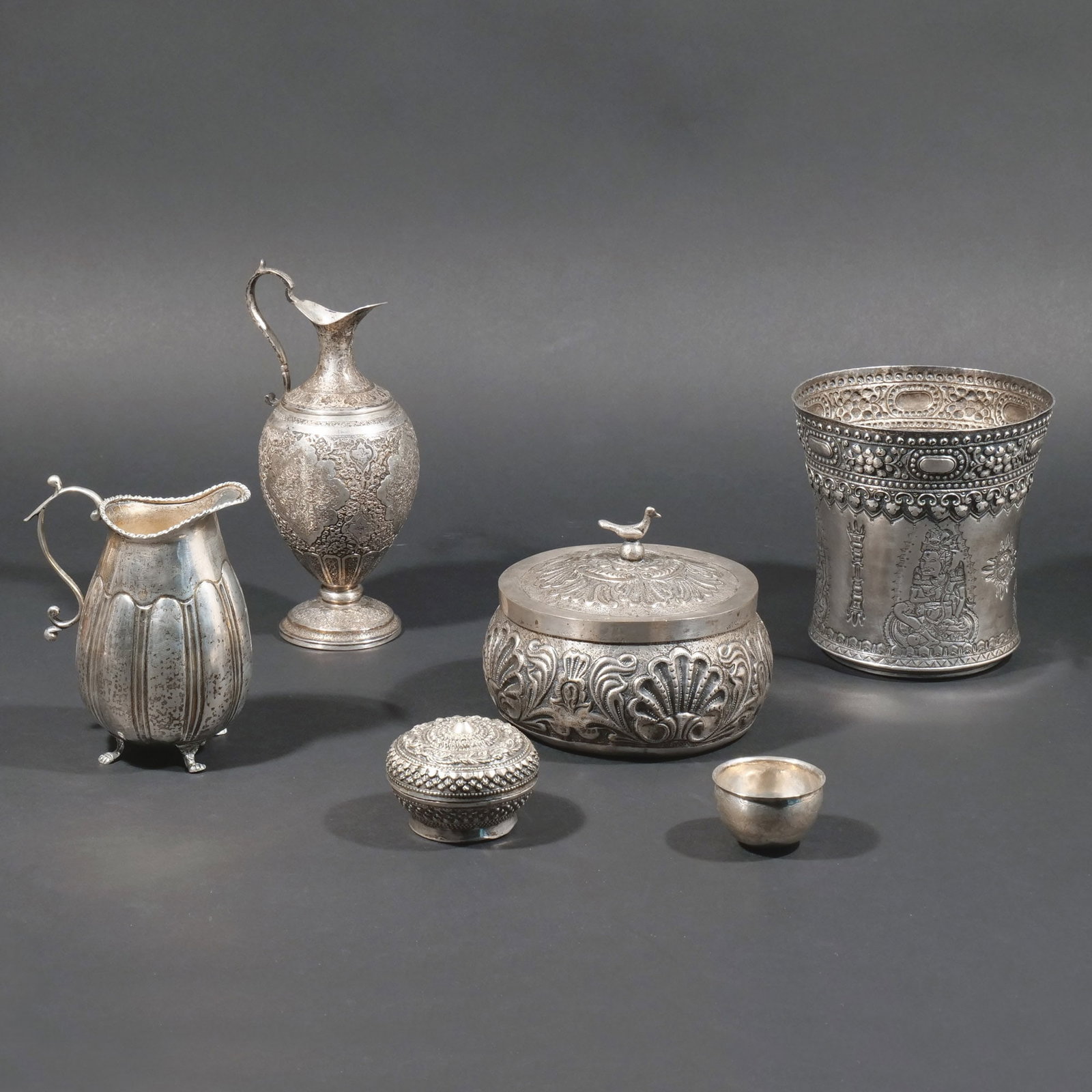 (6pc) BURMESE and OTHER SILVER: Including a large Burmese repousse vase with mythical figures between arrows and other designs, an Iranian chased silver ewer, an unmarked South American(?) covered jar with bird finial and scalloped 