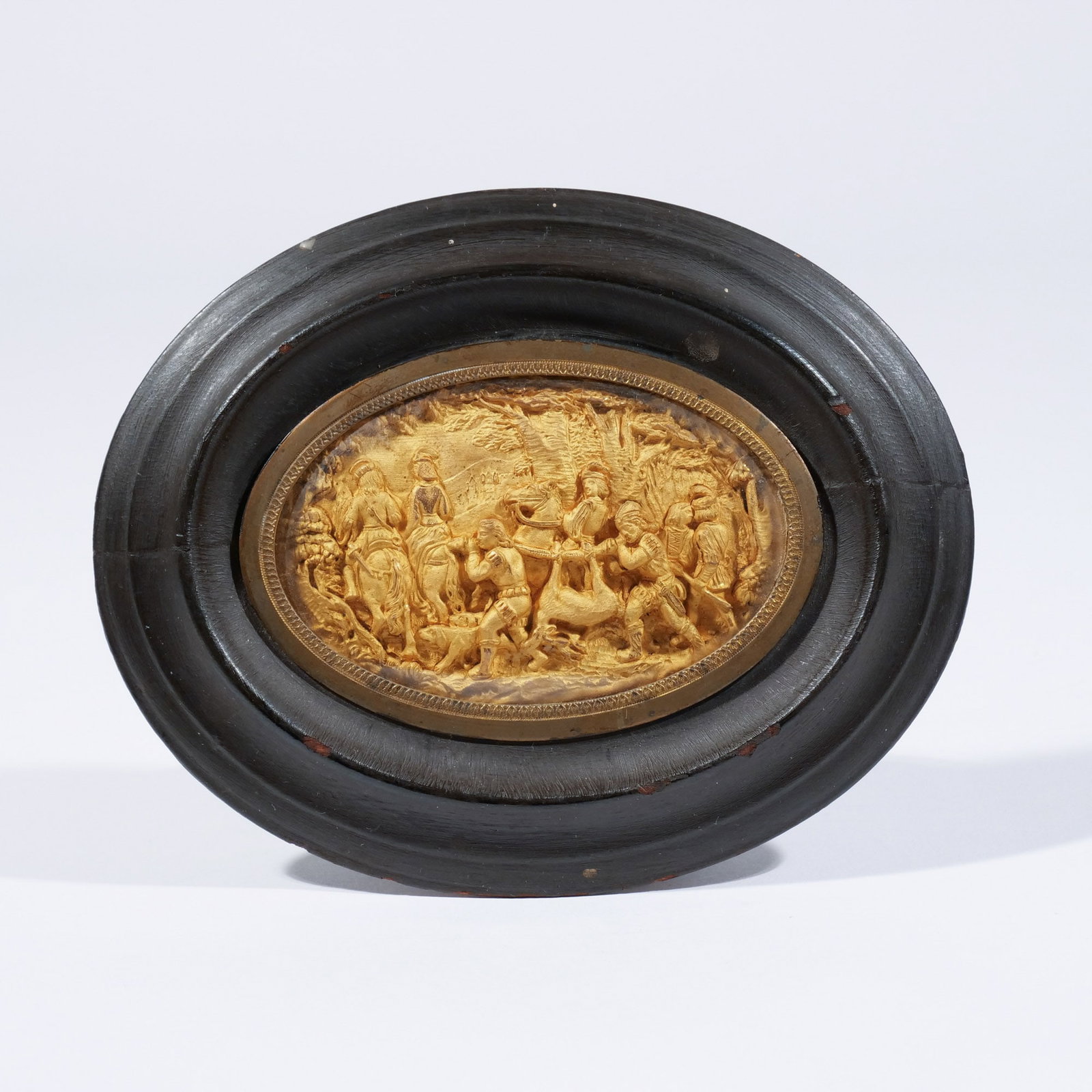 CONTINENTAL GILT METAL BAS RELIEF OVAL PLAQUE: 19th century, depicting a scene with figures returning from the hunt, framed h. 3-1/4 w. 2-1/8 in. overall: 5-1/2 x 4-1/2 in. (framed) Provenance: Descent through the consignor grandmother's estate
