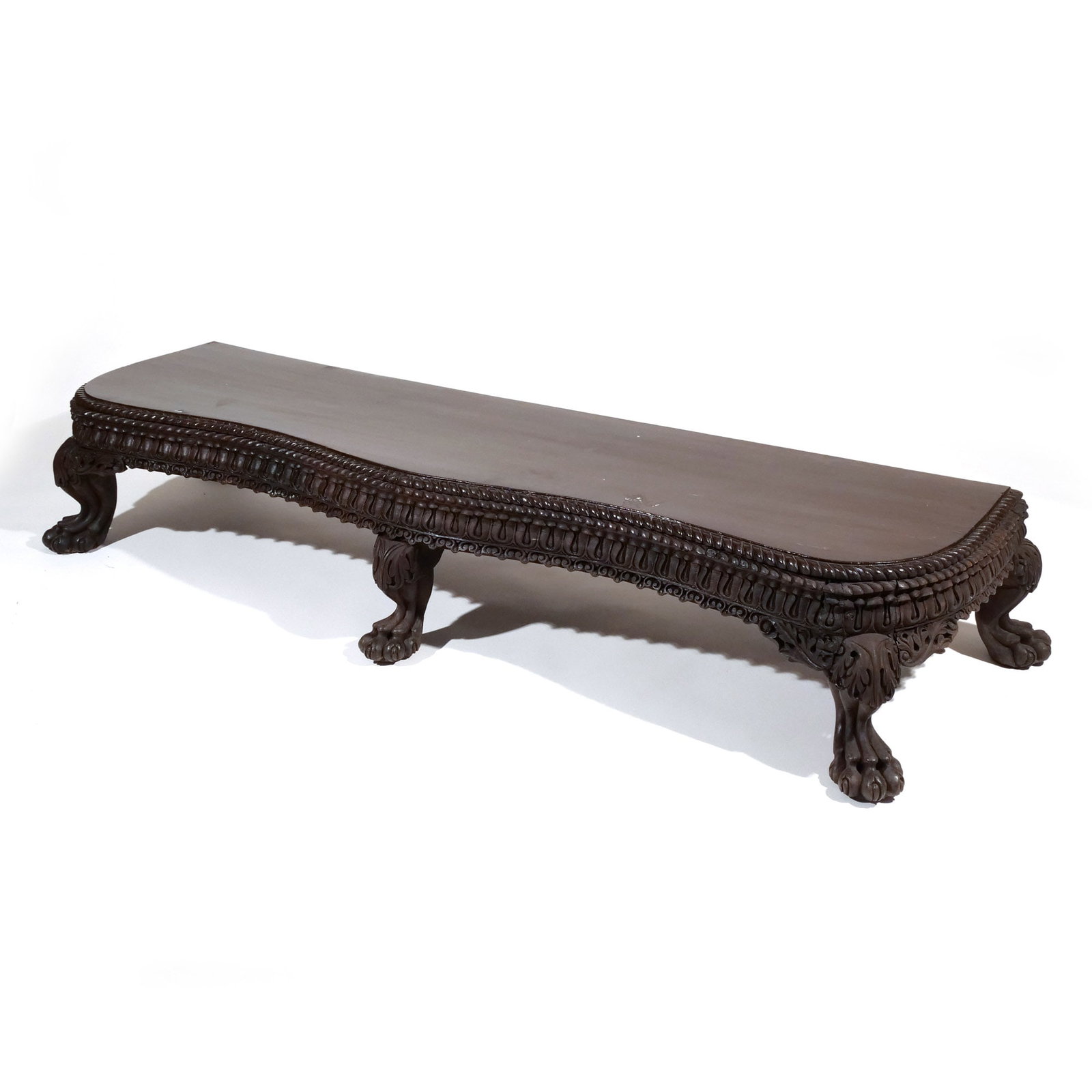 ANGLO-INDIAN CARVED LOW TABLE STAND: Late 18th / early 19th century, having a serpentine front, bowed sides and finished straight back with overall carved frieze, resting on carved paw feet with acanthus carving on knee h. 13 w. 71 d.