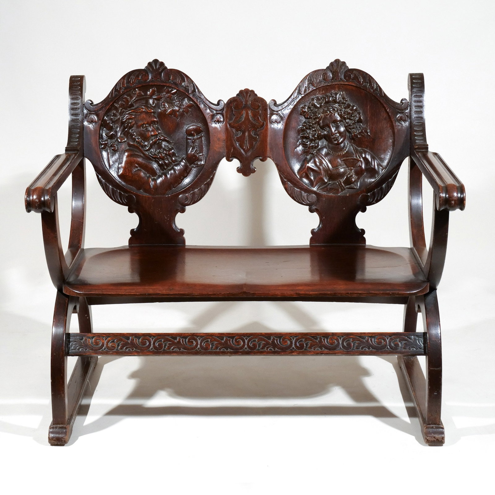 ITALIAN RENAISSANCE STYLE CARVED PORTRAIT BENCH: Savonarola-style, late 19th / early 20th century, with hand-carved figural scenes on the backrest h. 39-1/2 w. 45-1/2 d. 31-1/2 in. Provenance: Descent through a Waccabuc, NY family [In Situ Item] Thi