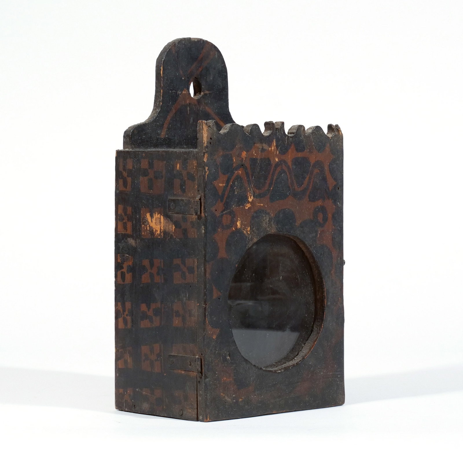 FOLK ART PAINTED WATCH HUTCH / CLOCK HOOD: 19th century, with shaped crest and circular aperture, painted in black with geometric designs h. 4 w. 11 d. 6 in. Provenance: Private collection, Bernardsville, NJ [In Situ Item] This item will not