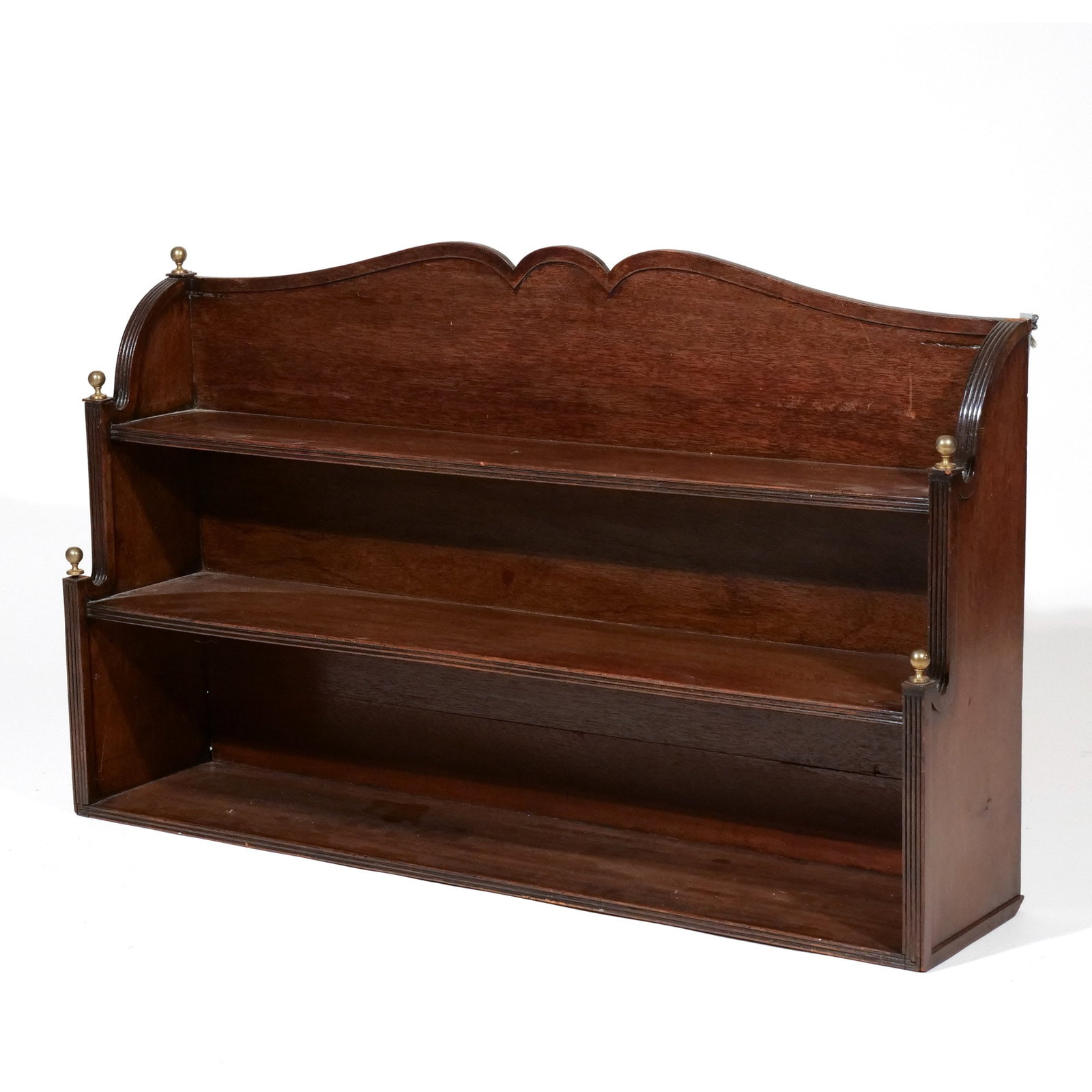 FEDERAL MAHOGANY HANGING SHELF: 19th century, a waterfall open three-tiered hanging shelf having molded serpentine crested backboard, flanked by reeded stiles with brass finials h. 24-1/2 w. 42 d. 9 in. Provenance: Private