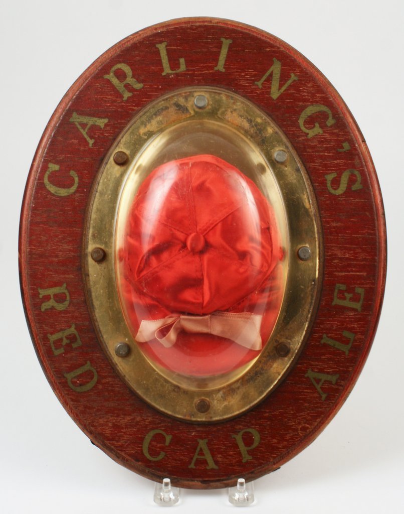 41) RED "CARLING'S ALE" CAP encased in a port-hole: 41) RED "CARLING'S ALE" CAP encased in a port-hole type oval frame, H: 14" W: 11"