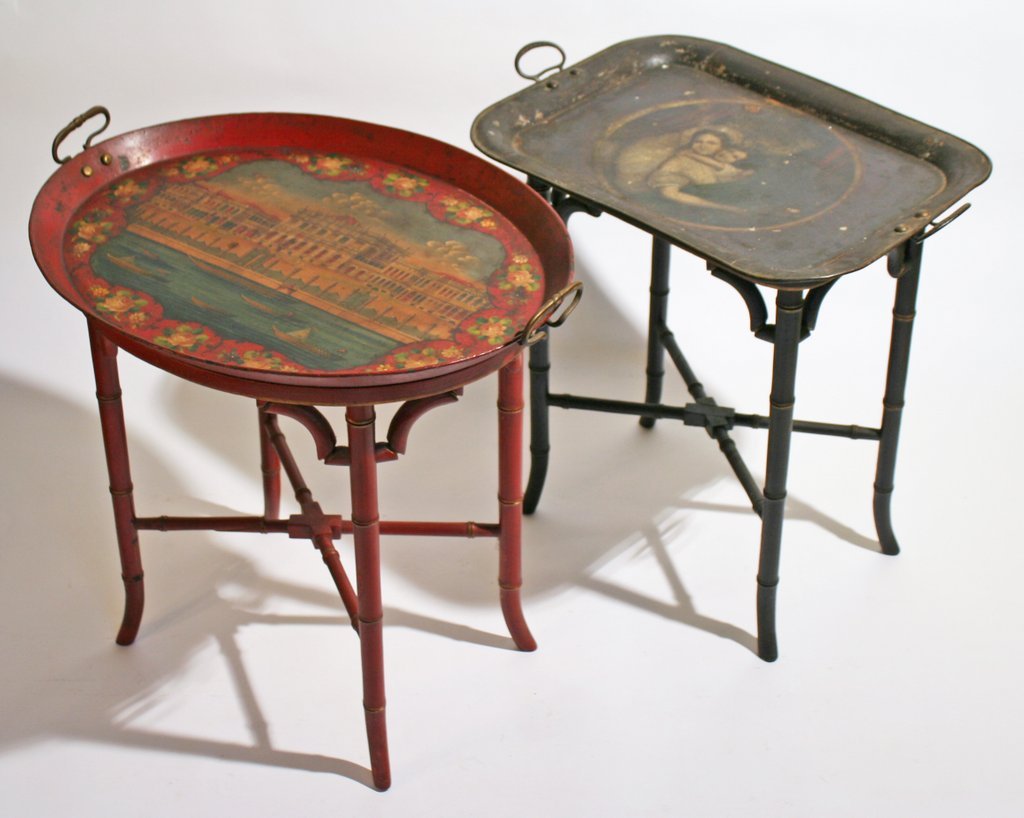 120) TWO TOLE TRAYS ON STANDS, one in scarlet red: with a scene showing a Venetian palace, H: 20 ½" W: 21 ½" D: 16 ½"; the other in black with a scene of a mother and child; the red tray with a break at the handle