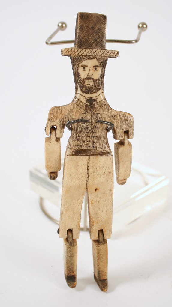 387) SCRIMSHAW FIGURE OF ARTICULATED MAN in a suit: with a top hat, carved whale bone with pen-work, H: 7 ½"