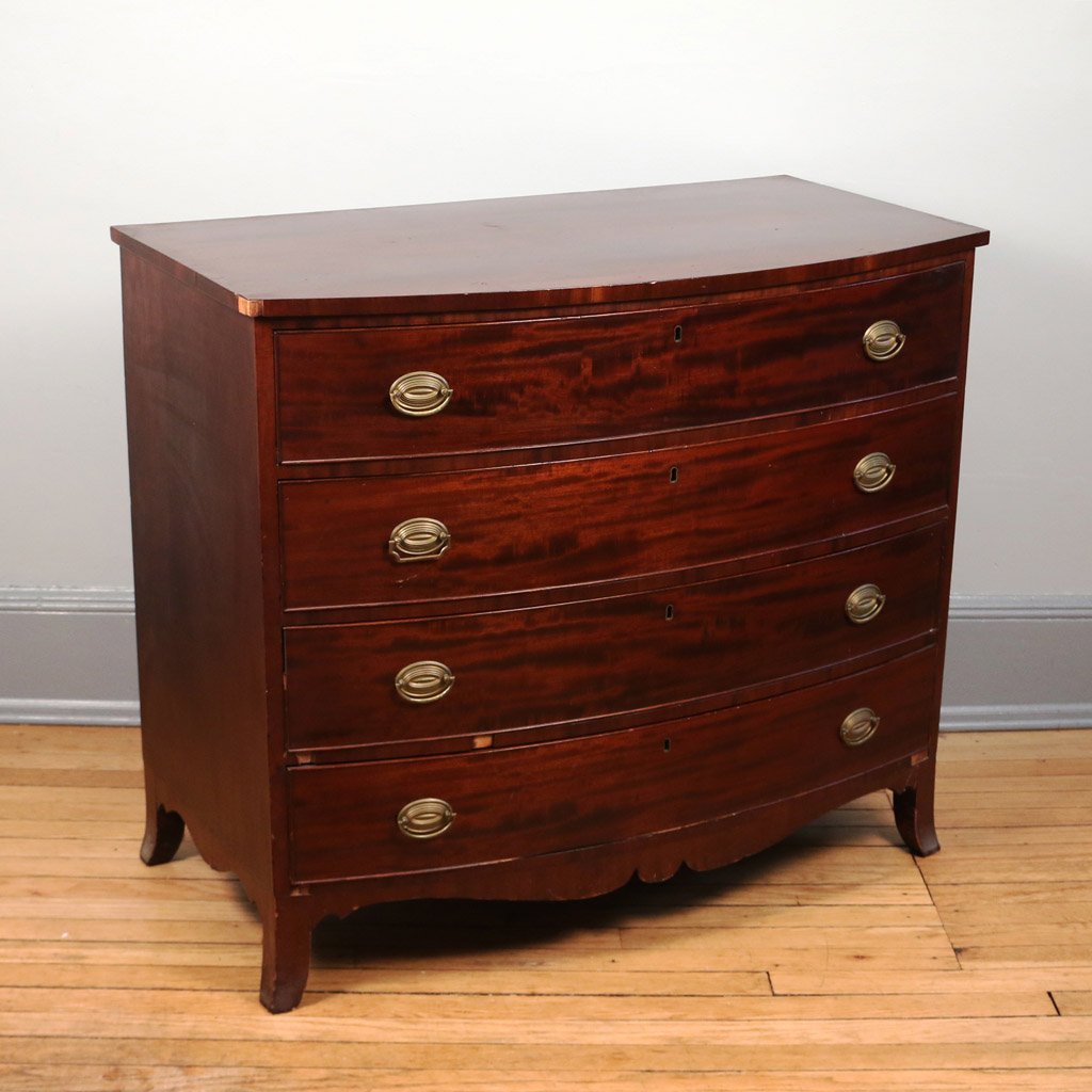 AMERICAN HEPPLEWHITE BOW FRONT CHEST: mahogany and mahogany veneer, with four drawers over a shaped apron and splayed feet, h. 36" w. 41 1/2" d. 22", missing a few pieces of veneer and one pull with a replaced handle
