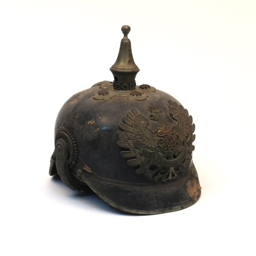 WWI PRUSSIAN MILITARY HELMET: Leather and brass, having an eagle crest clutching an inscribed ribbon; pointed finial; appx. h. 8-1/2"