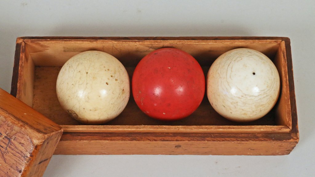 THREE ANTIQUE BILLIARD BALLS: By Brunswick-Balke Collender Co., including two white and one red ball, each approx. 2" in diameter, with original wood box (8" x 2 3/4" x 3 1/4")