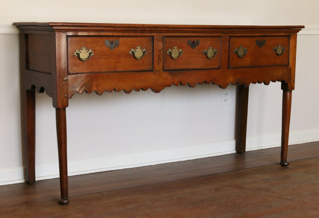 ENGLISH ELM DRESSER: Early 19th Century, having three short drawers over a shaped apron, h. 34” w. 65” d. 19”