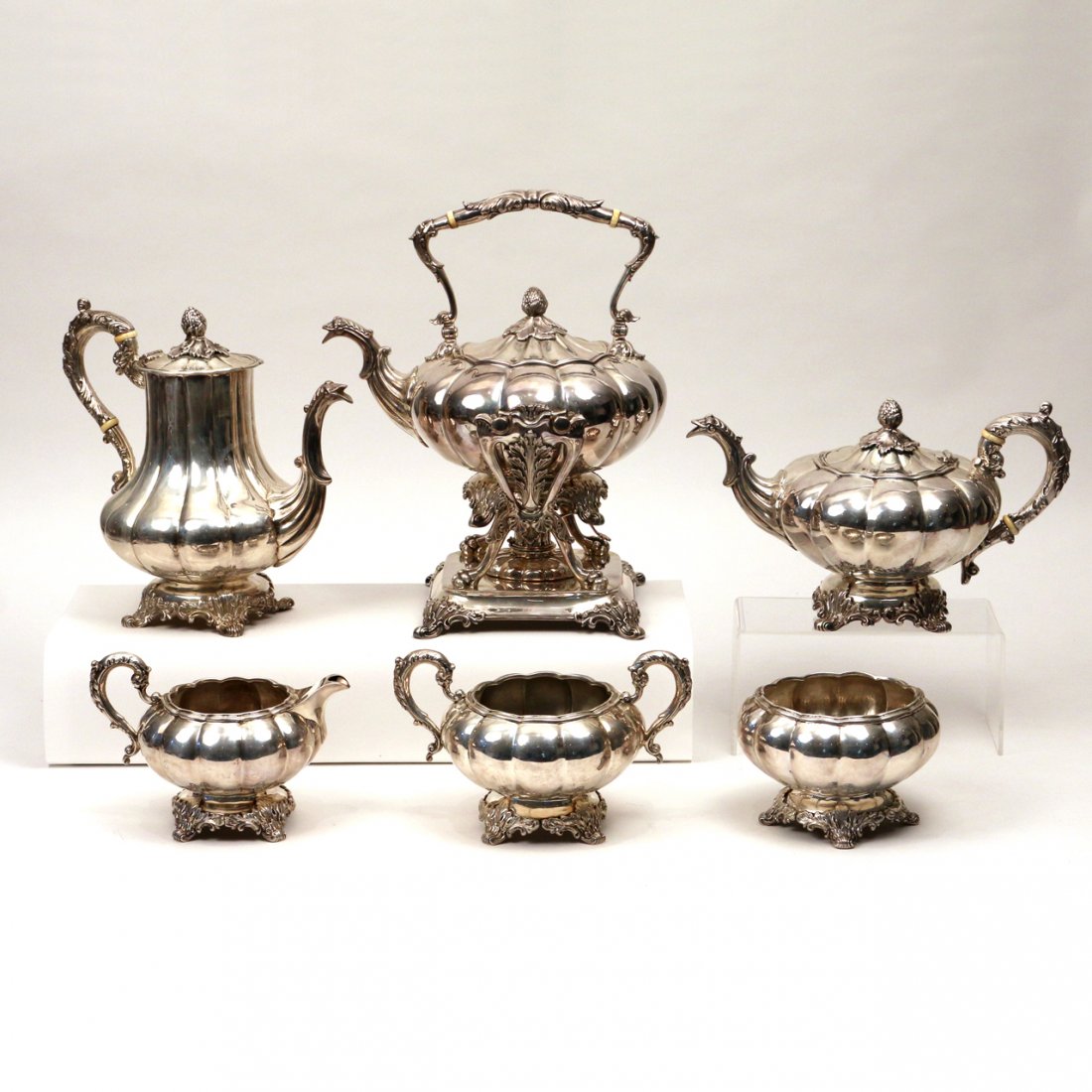 (6pc) STERLING SILVER COFFEE & TEA SERVICE: C. 1840 - Including an English Victorian Tiffany & Co. hot water kettle on stand, a teapot, a coffee pot, a creamer, a sugar bowl, and a waste bowl; all with gadrooned bodies, acorn finials, and appea