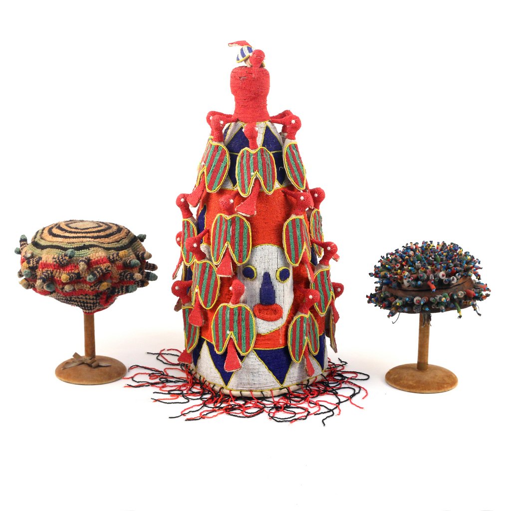 THREE AFRICAN HATS: Including a Yoruba beadwork priest's crown decorated with birds and faces in orange, blue and white, h. 23-1/2 in.; a woven striped skullcap, dia. 12 in.: and a beaded gourd skullcap decorated with cl