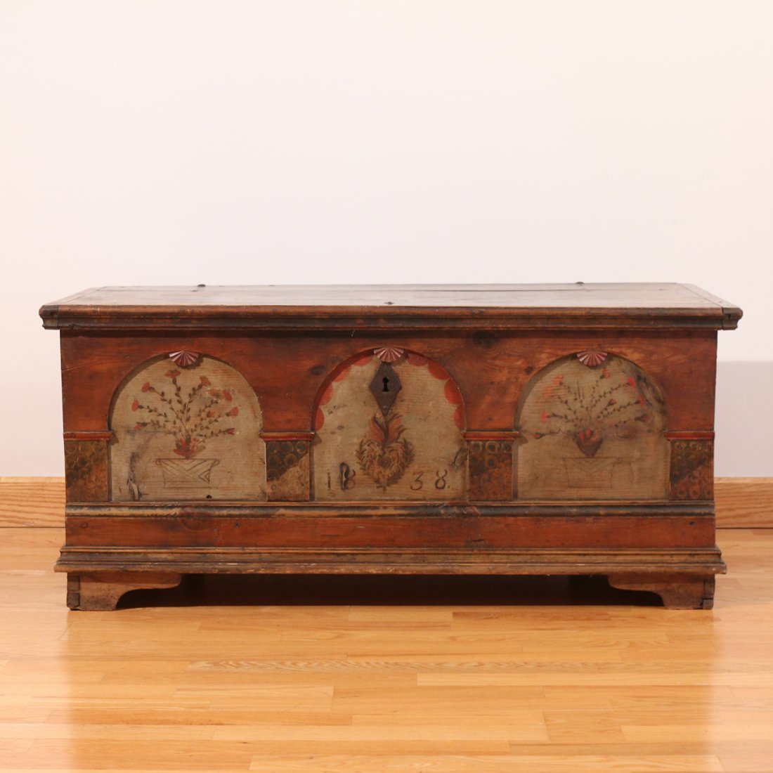 PAINT DECORATED PINE BLANKET CHEST: 19th Century, with three recessed arched window niches on the front headed by carved fans, the central niche dated ‘1838’, h. 20", w. 45 1/2", d. 22 1/2", old paint with rose nail-head and peg con