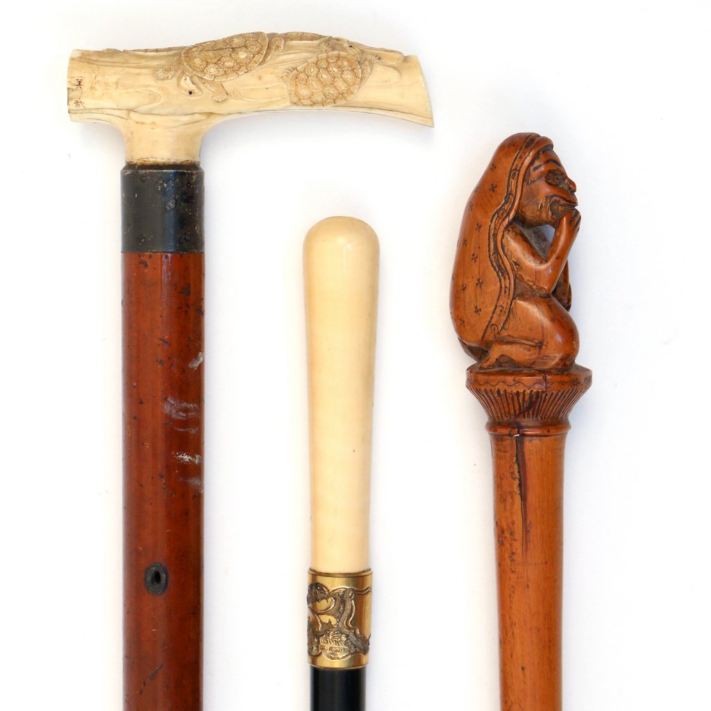 THREE ANTIQUE WALKING STICKS: Including one with an antique ivory handle carved with turtles; one with a turned antique ivory handle and a gold plated neck; and one with a primitive carved boxwood figure of a man, 34 1/2 - 35 1/2 